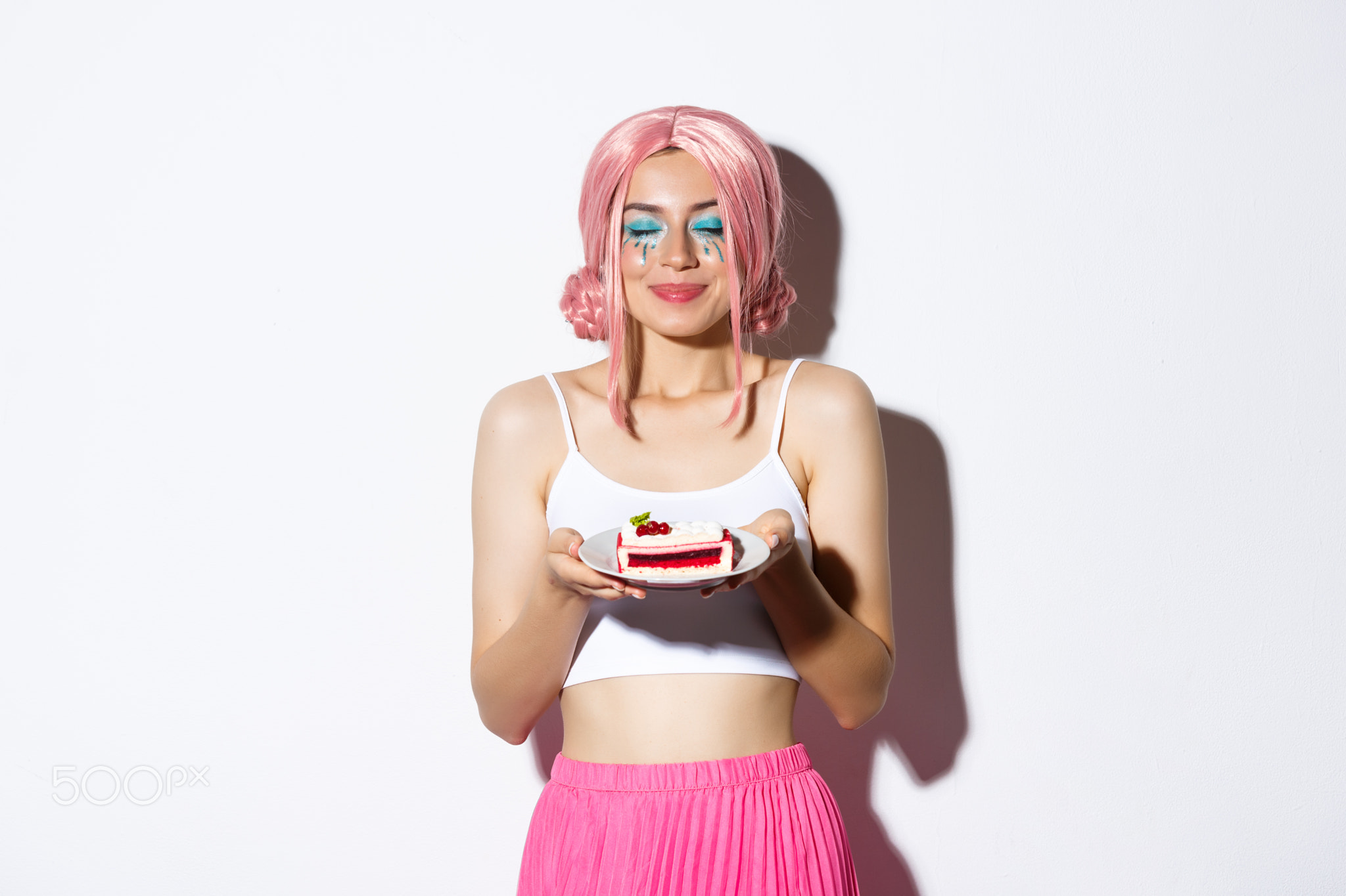 Image of beautiful girl in pink wig close eyes and smelling tasty cake
