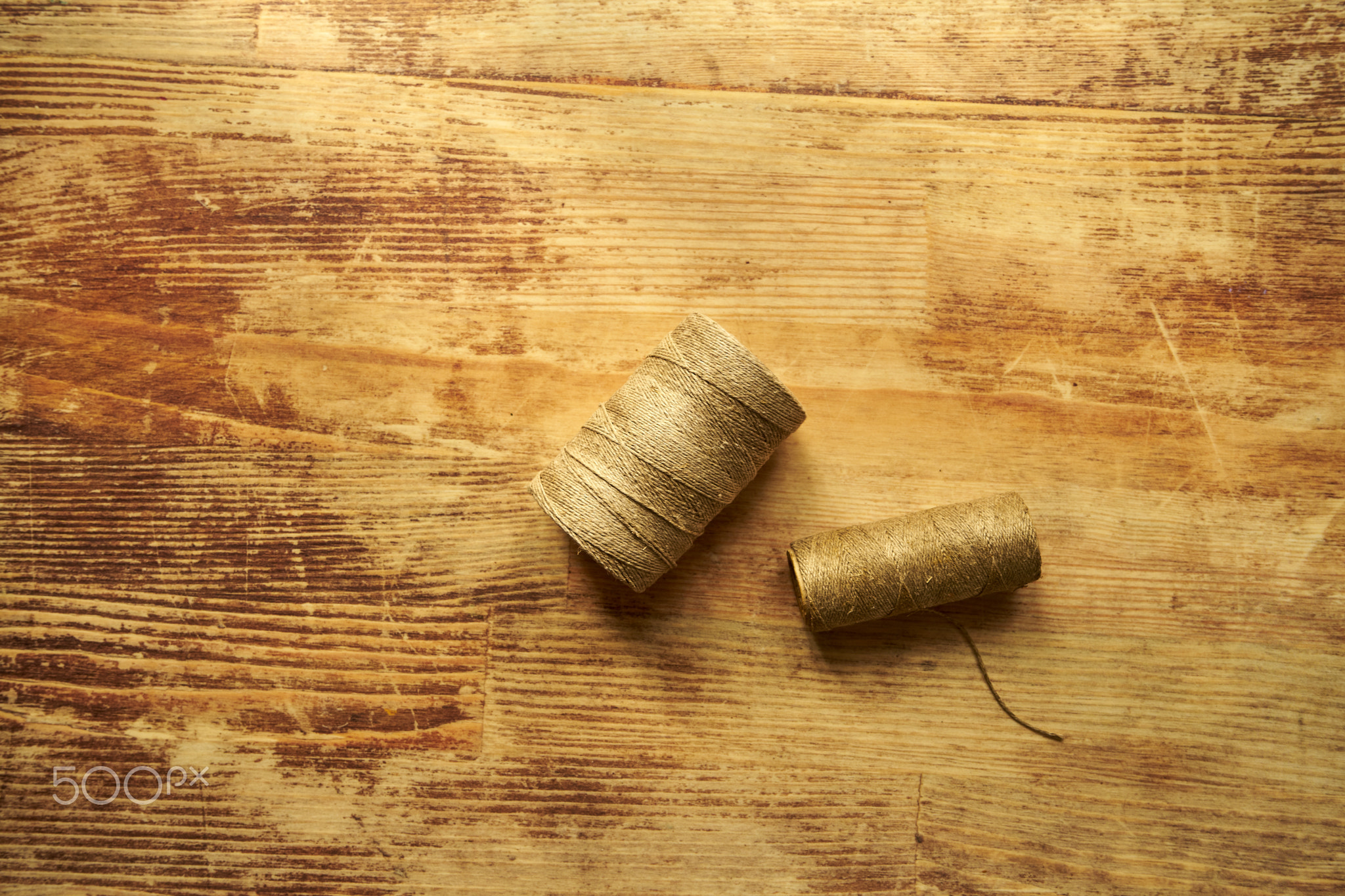 Two spools of twine on a wooden table