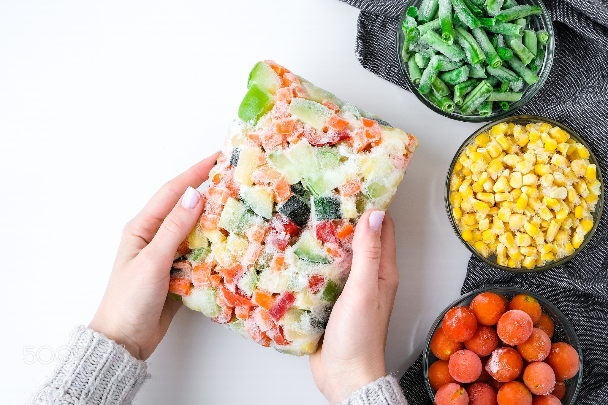 Mixed vegetable frozen food briquette in female hands. Preparing