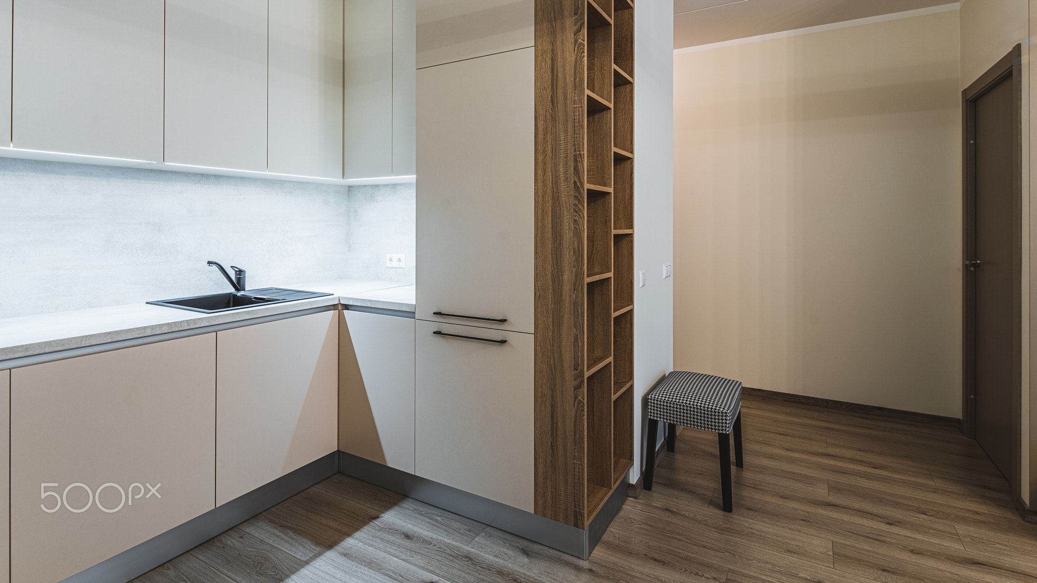 Modern interior. Kitchen in apartment. Beige cabinets. Wooden shelves.
