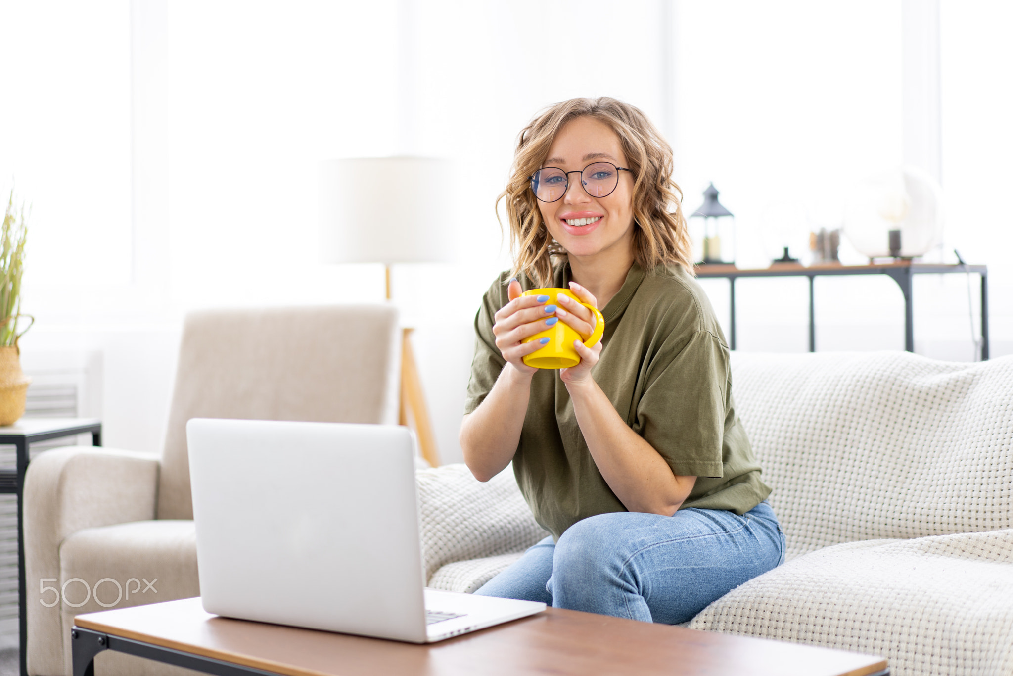 Woman glasses using laptop computer while sitting sofa with big window