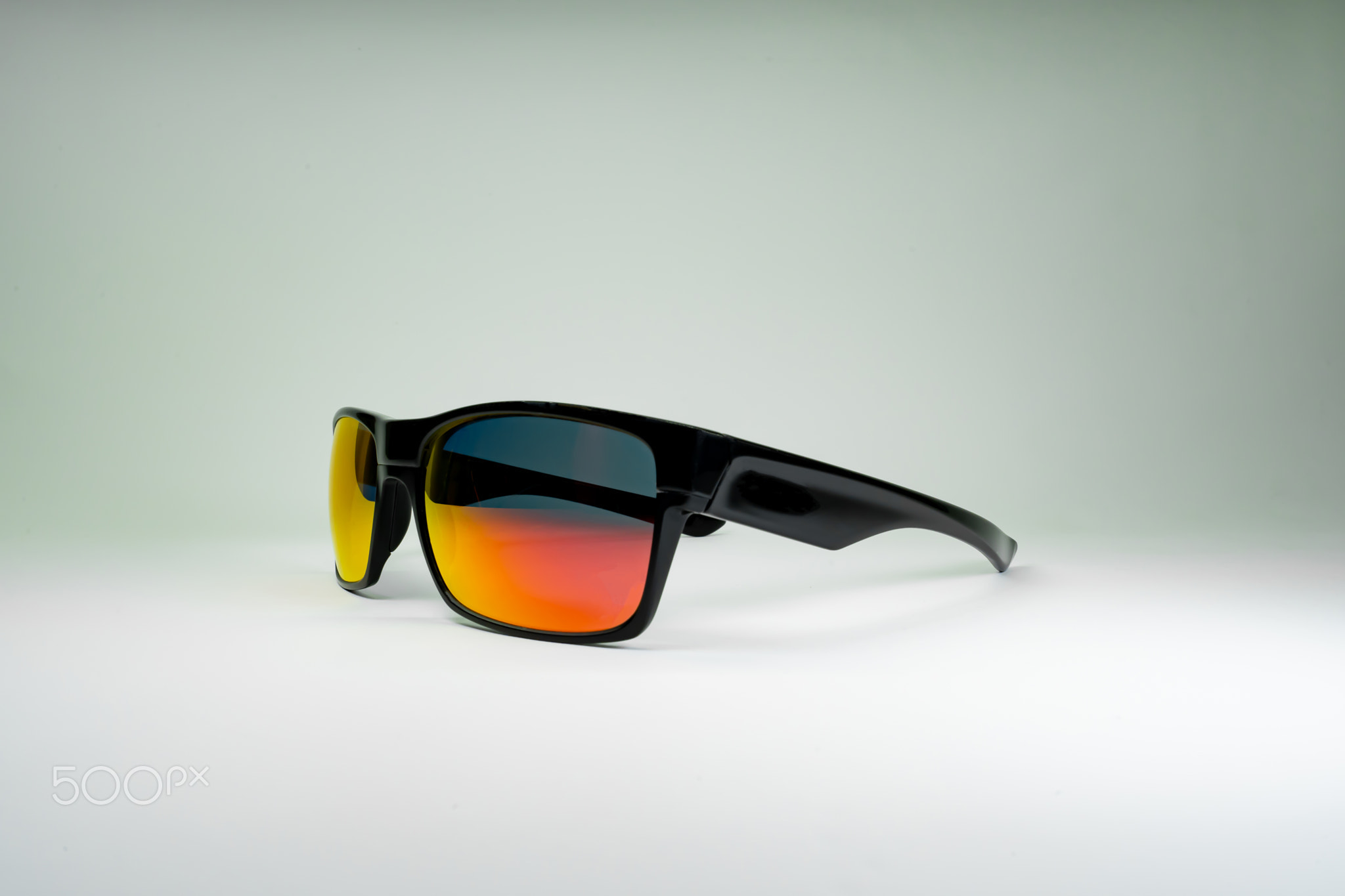Product photo of sun Glasses with orange glass and black frame on