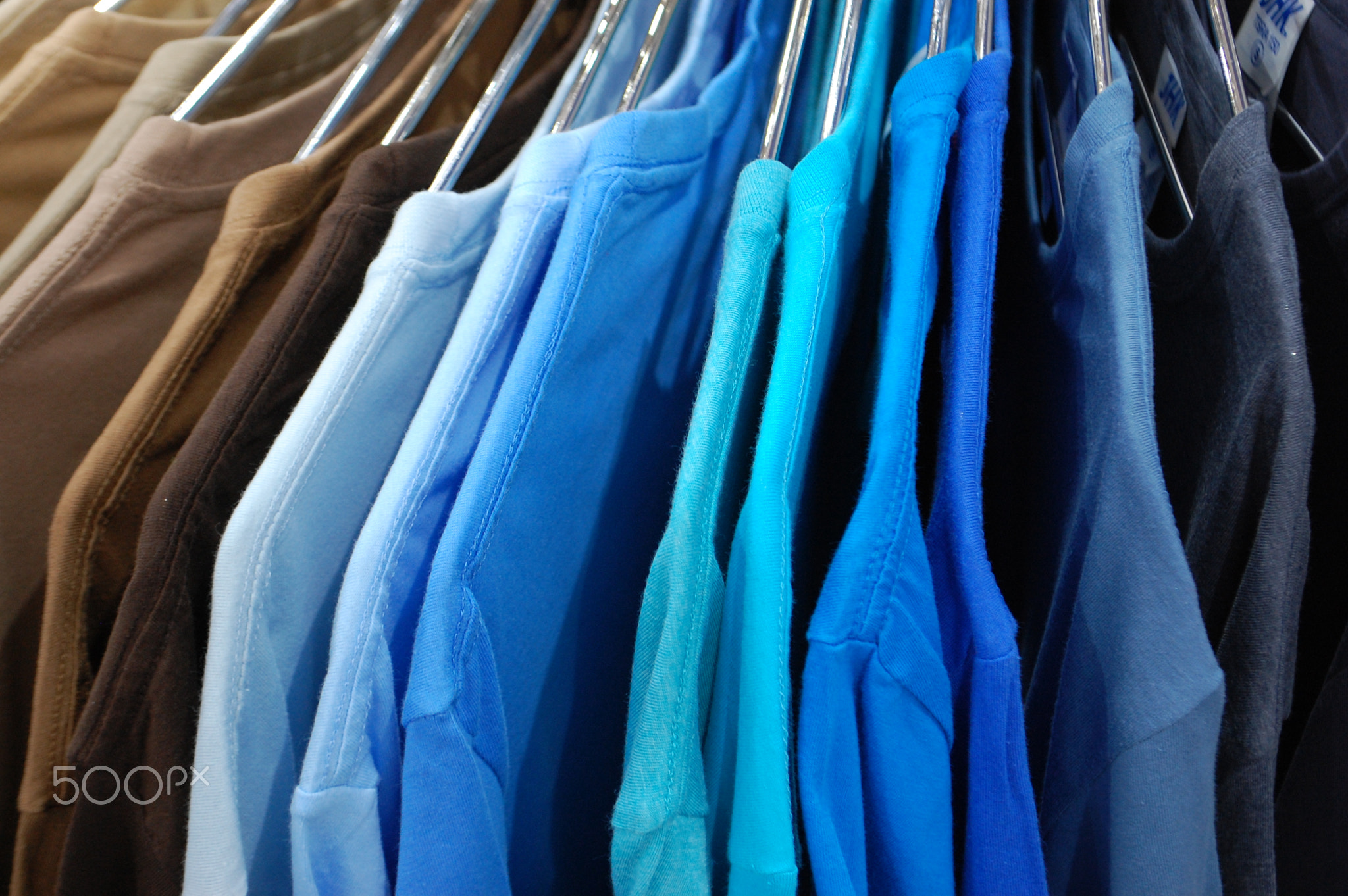 Rainbow colored clothes on hangers in a retail shop. Fashion and