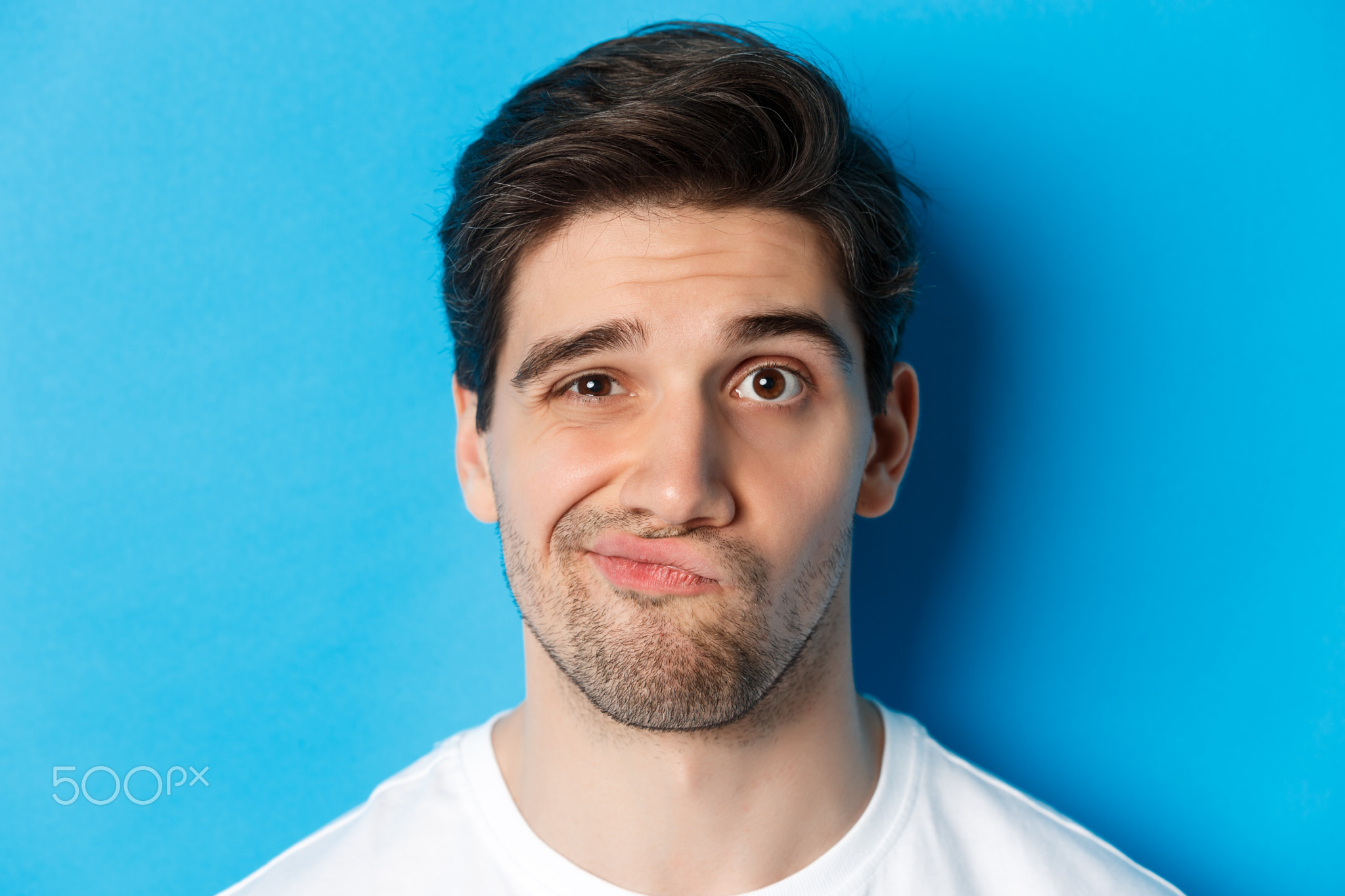 Headshot of skeptical guy looking at something unamusing, grimacing