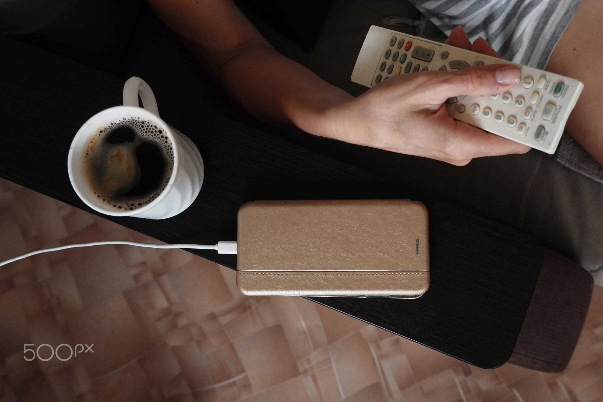 a woman switches TV channels with a remote control.Nearby, a cell