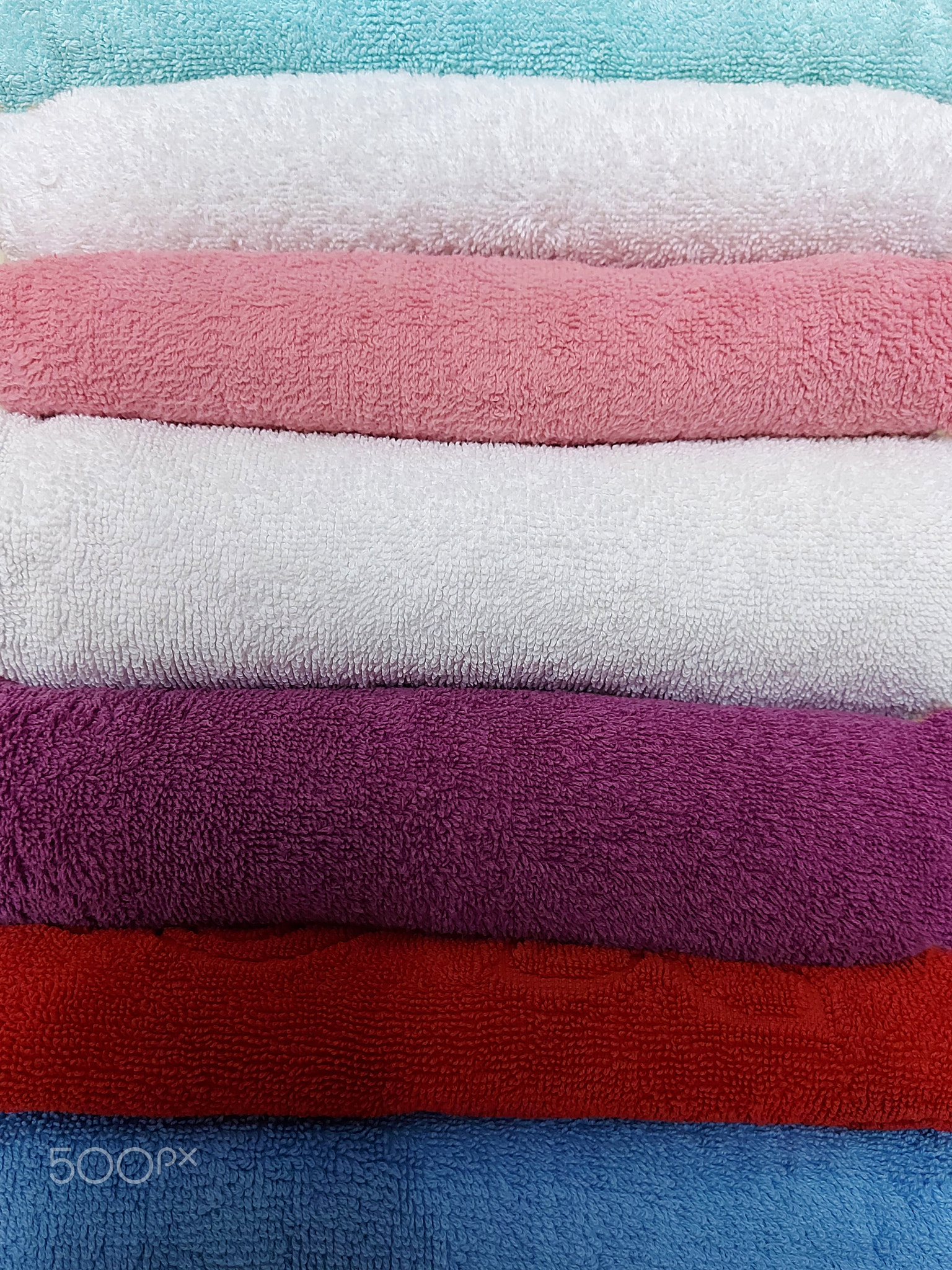 Multi-colored cotton terry towels are stacked