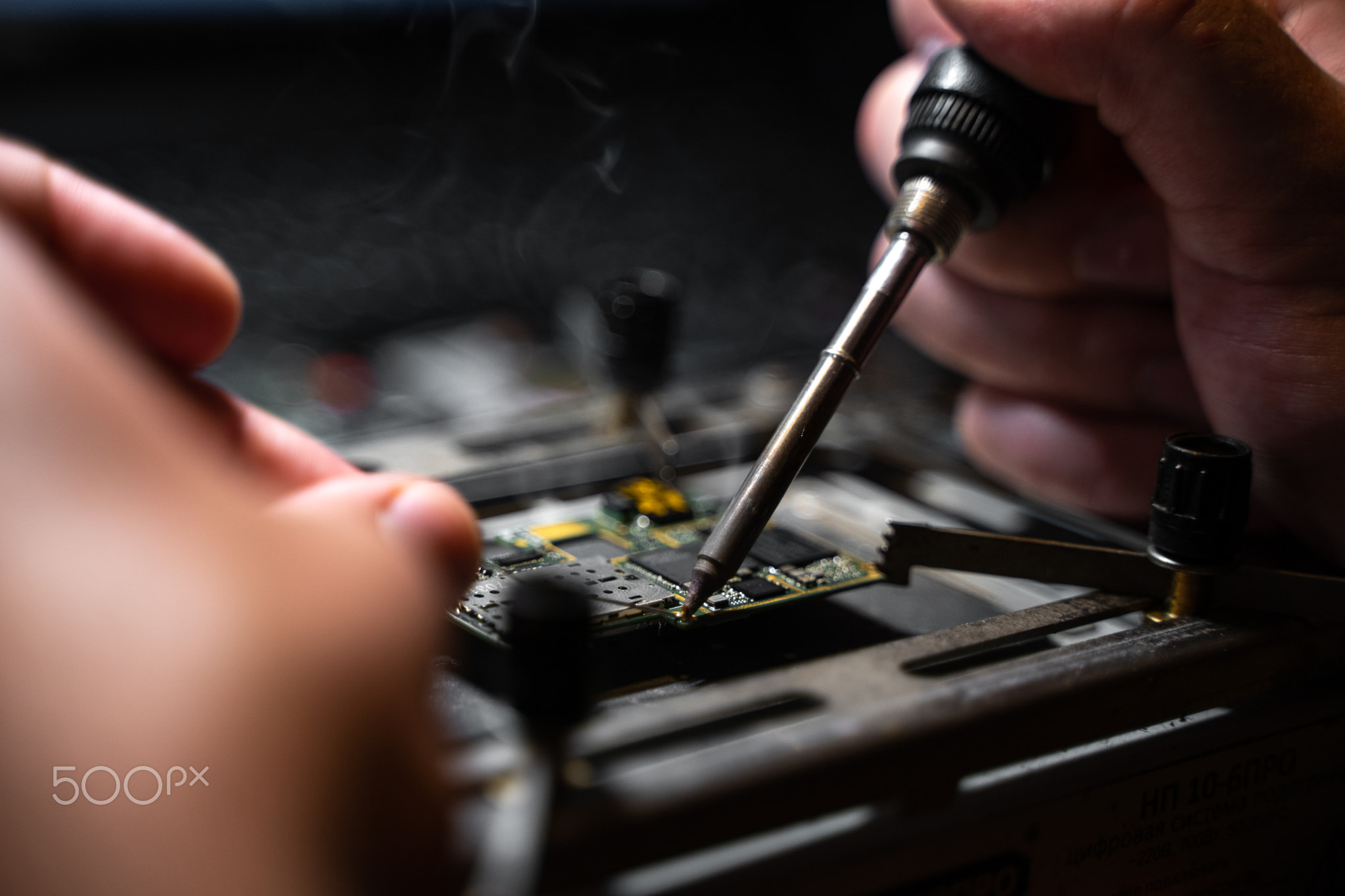 Soldering iron board of electronic device on the table, hands close up