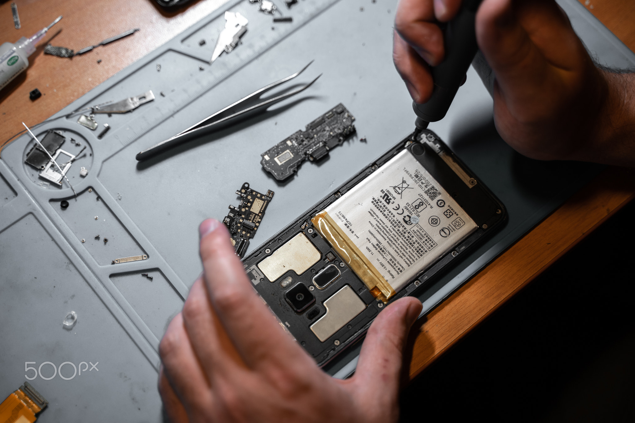 Hand technician repairing the smartphone with a screwdriver