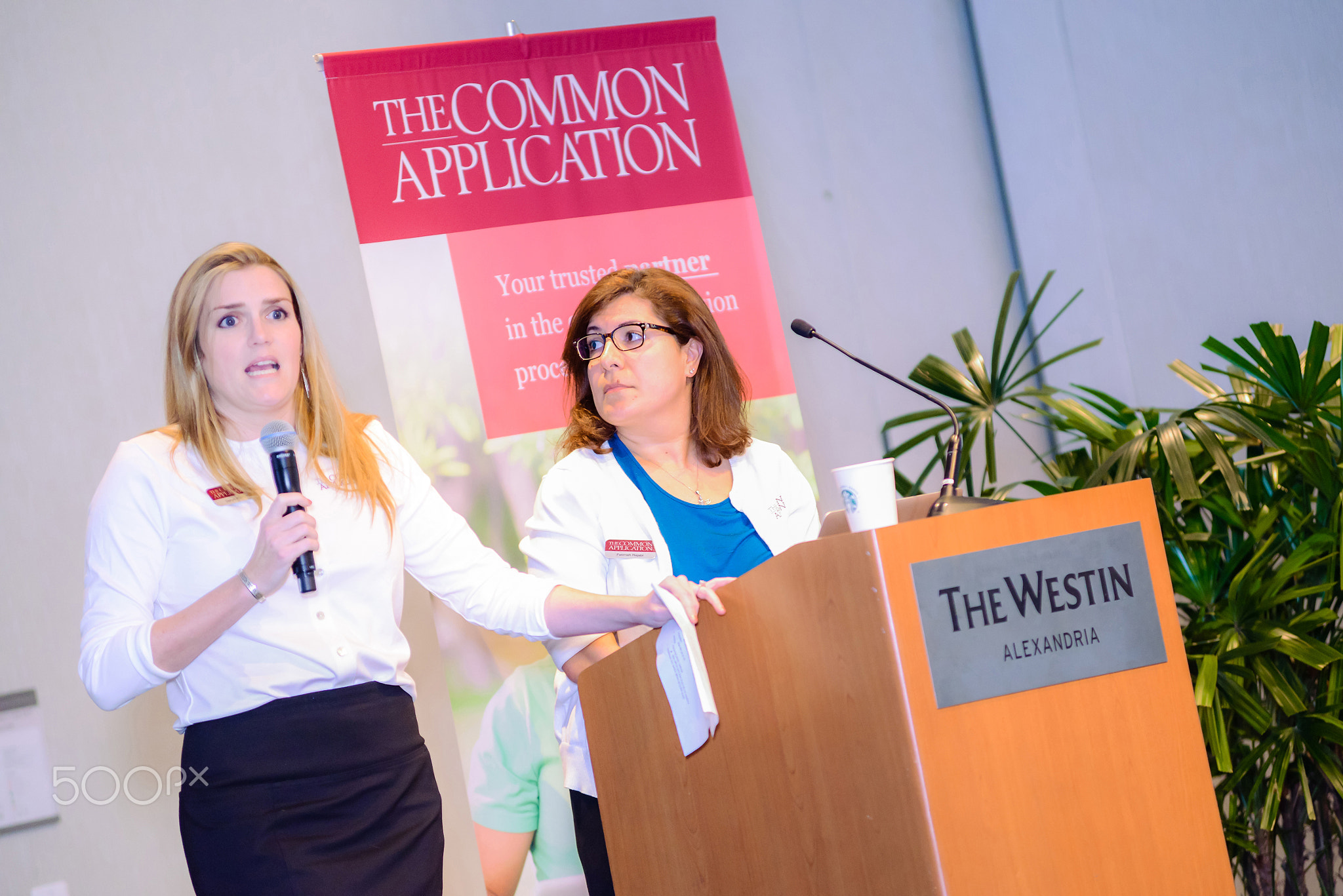 Two women speaking at a podium during a conference