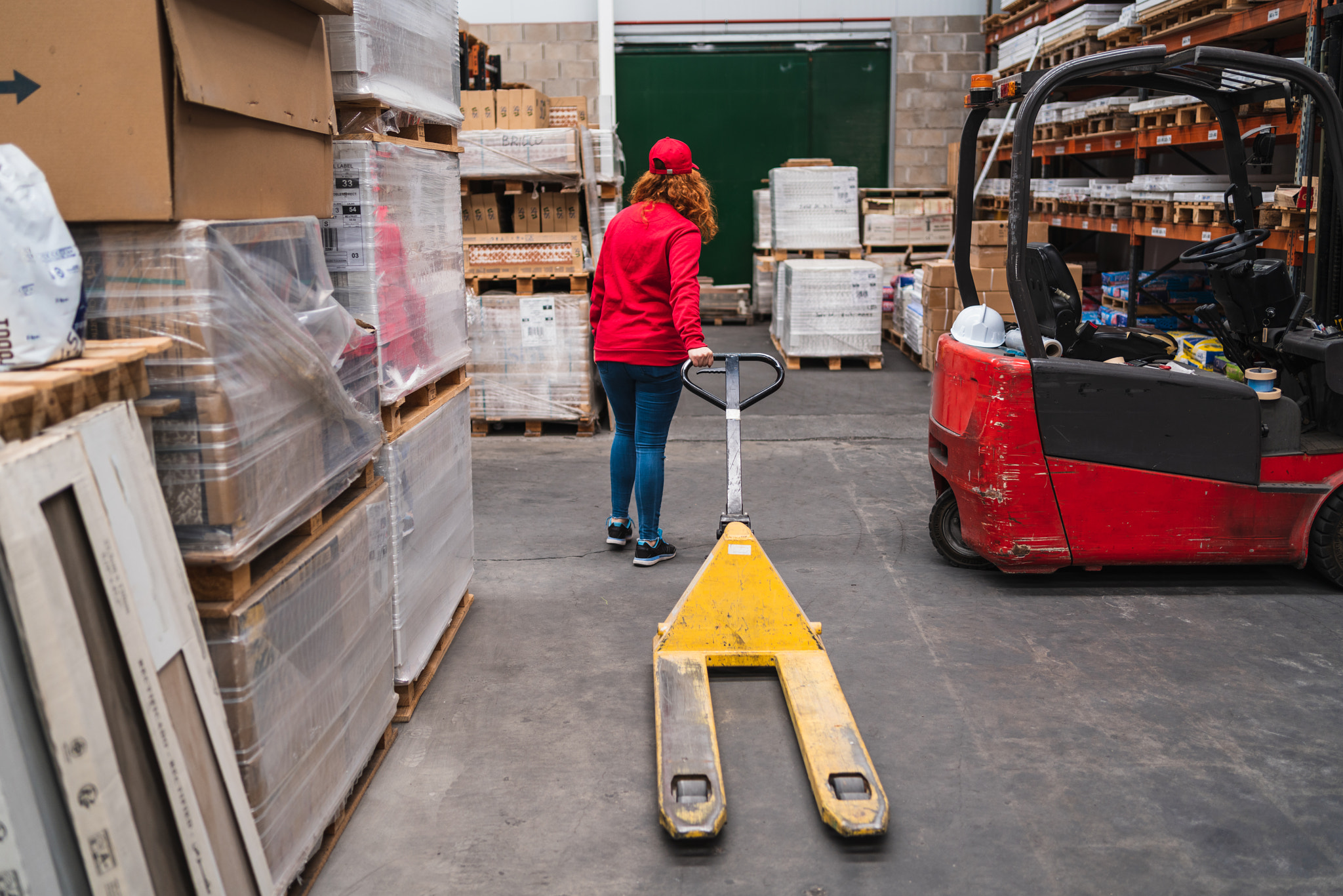 Female worker with a pallet truck in a warehouse