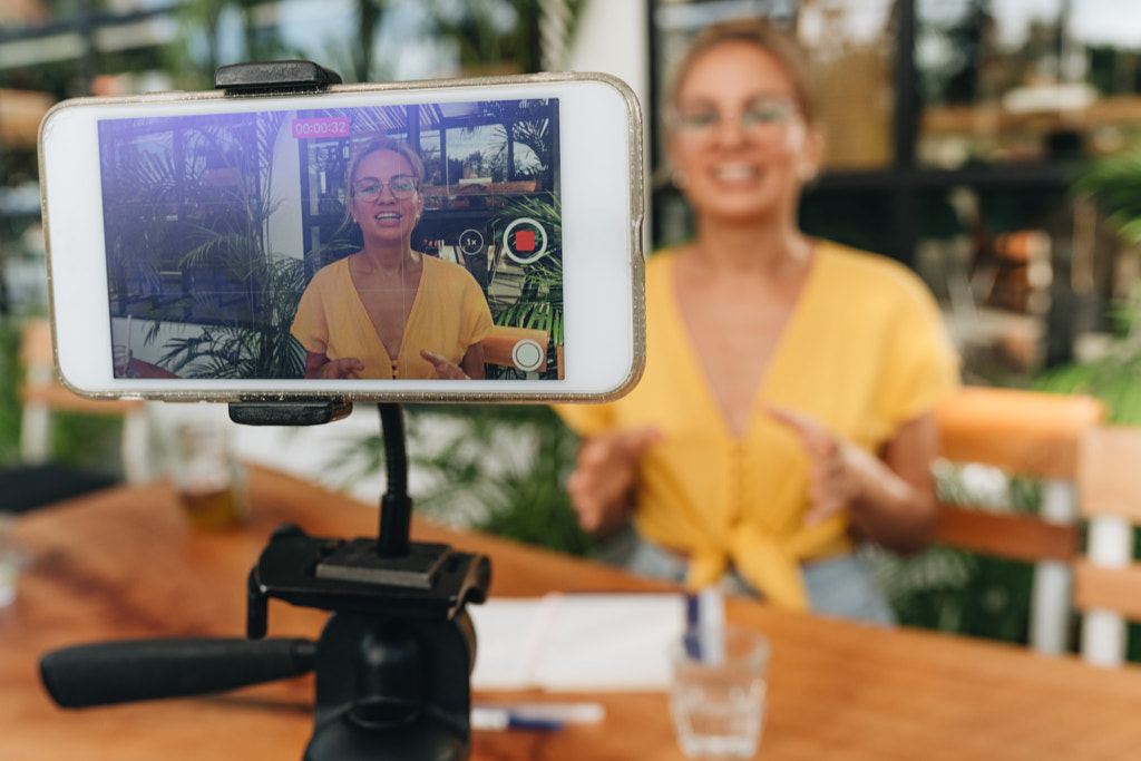 Happy vlogger influencer recording video with smartphone on a tripode. by Natalie Zotova on 500px.com