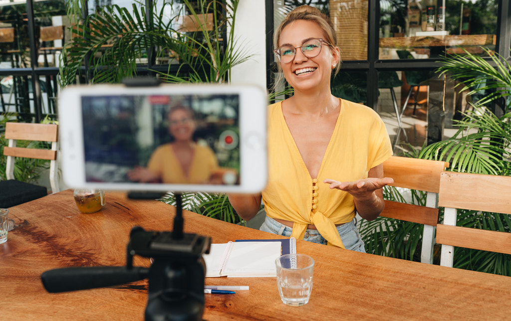 Happy vlogger influencer recording video with smartphone on a tripode. by Natalie Zotova on 500px.com