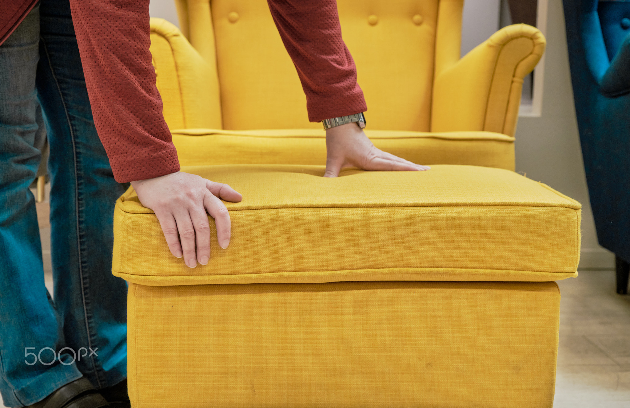 Woman in store chooses for buy chair and footstool made yellow fabric