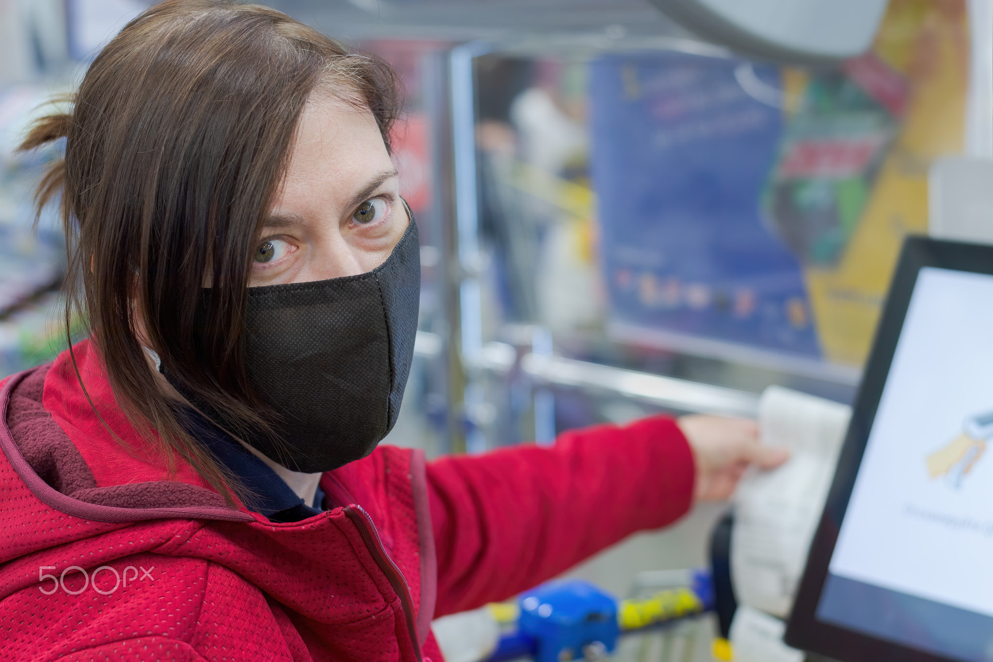 Girl in a medical mask pays for purchases in the store.