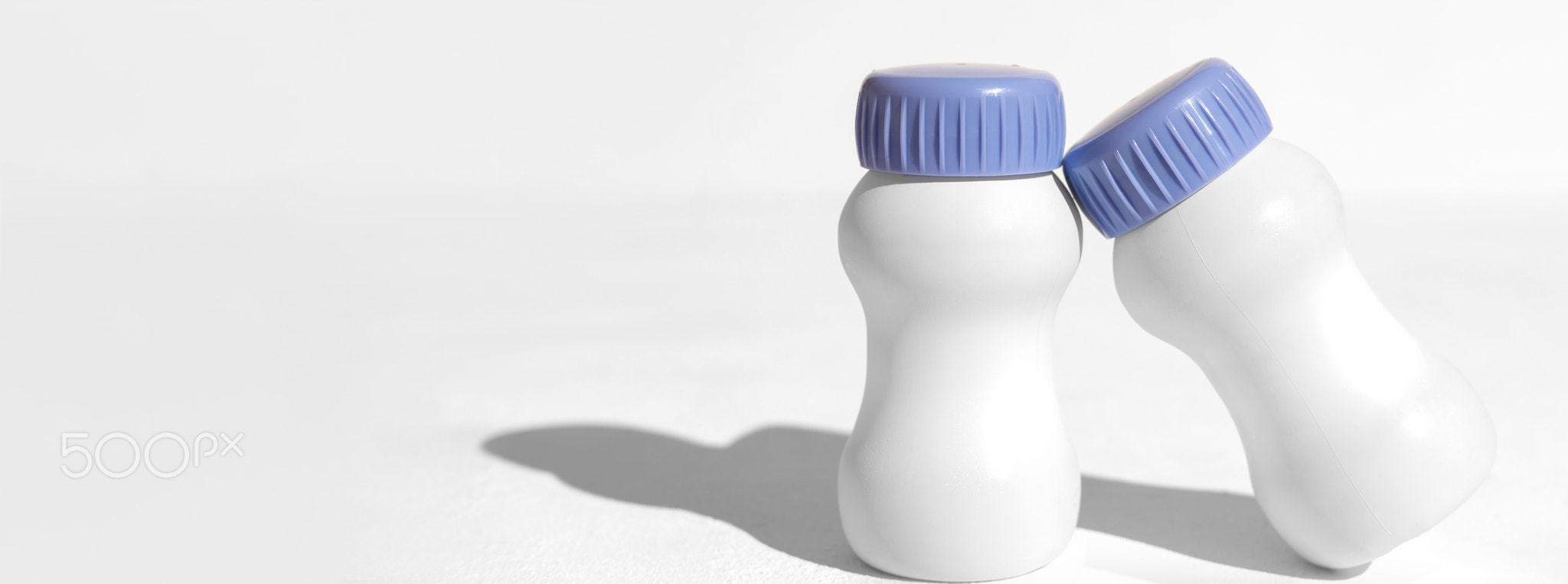 two white plastic bottles on white table. collagen drink to go. liquid