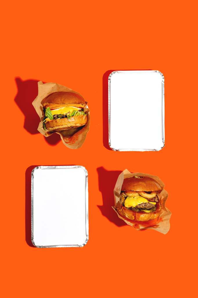 Two big burgers with cheese in package on orange background. by Valeriia Sviridova on 500px.com