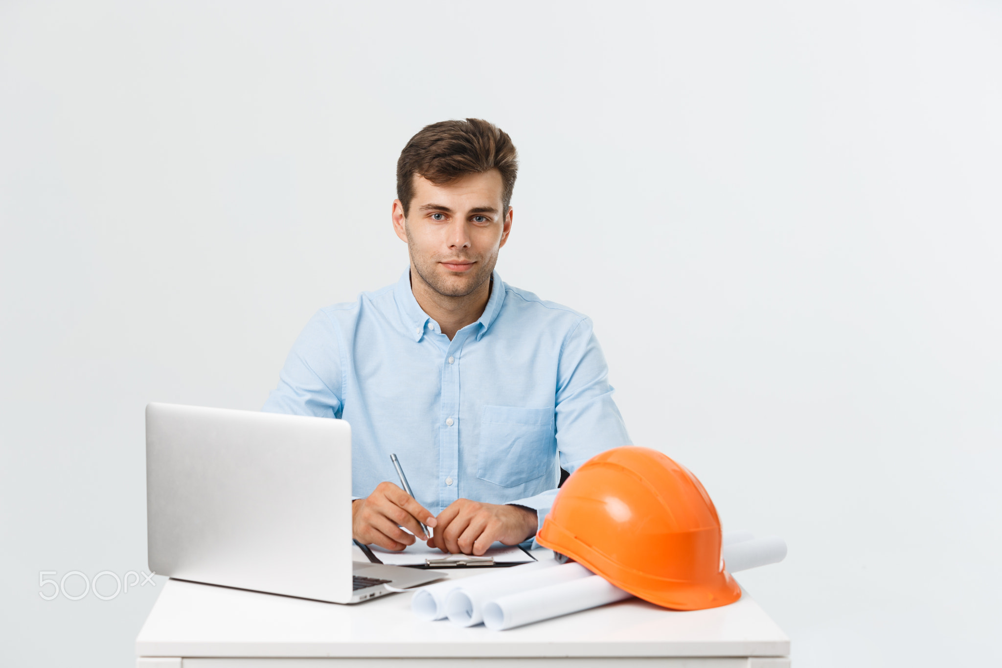 Handsome male construction engineer working in the office with laptop