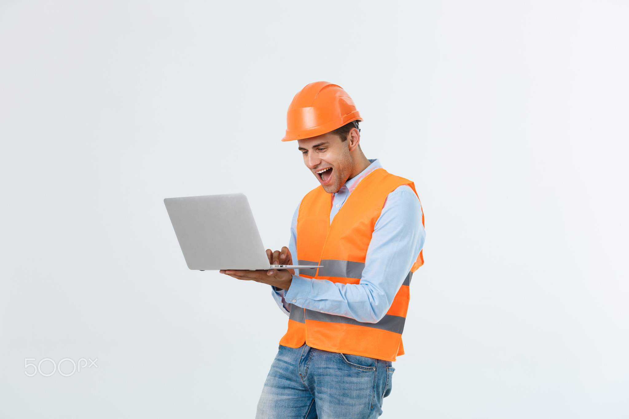 Adult man constructor surprised and working with laptop in helmet