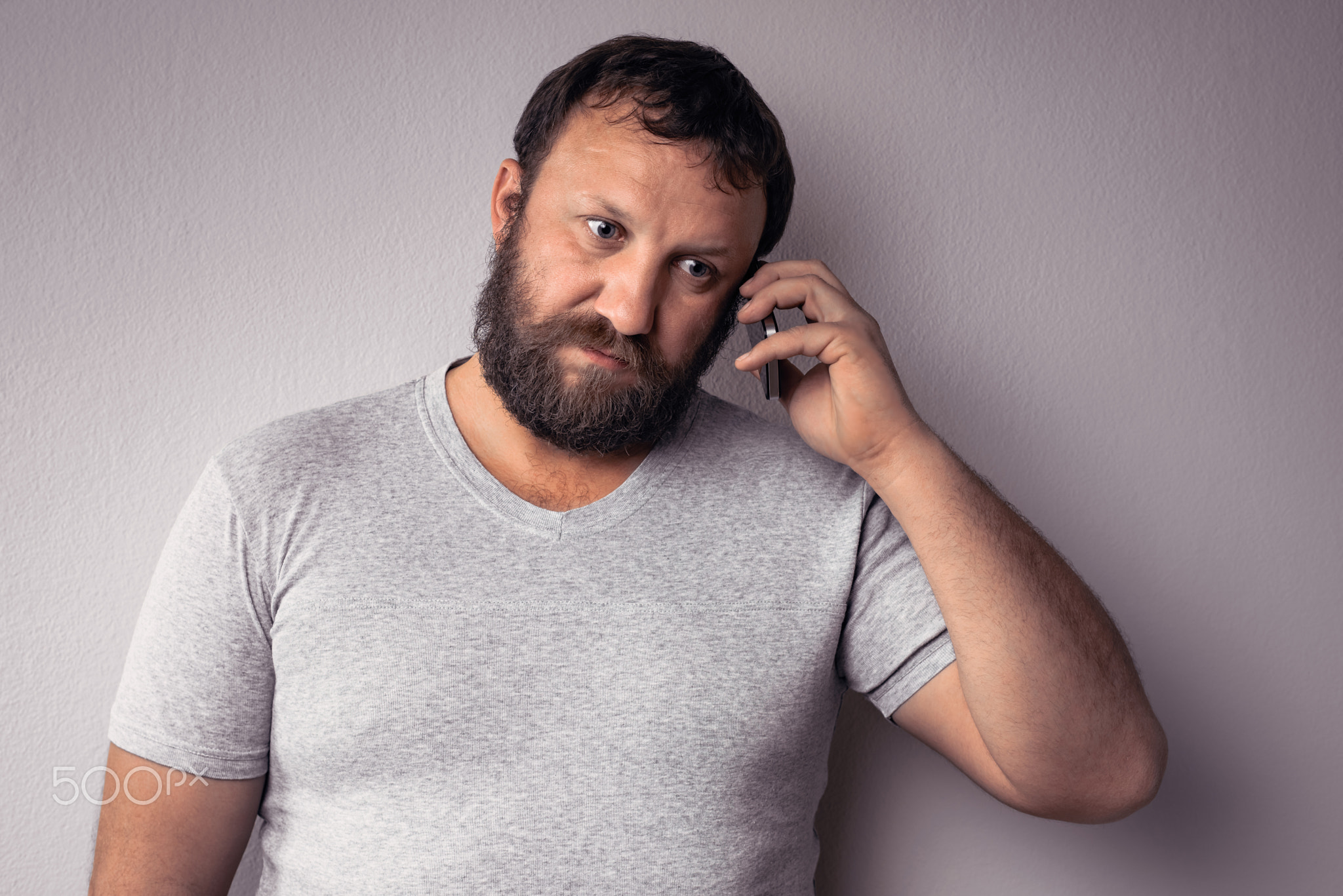 Bearded man in gray t-shirt holding mobile phone