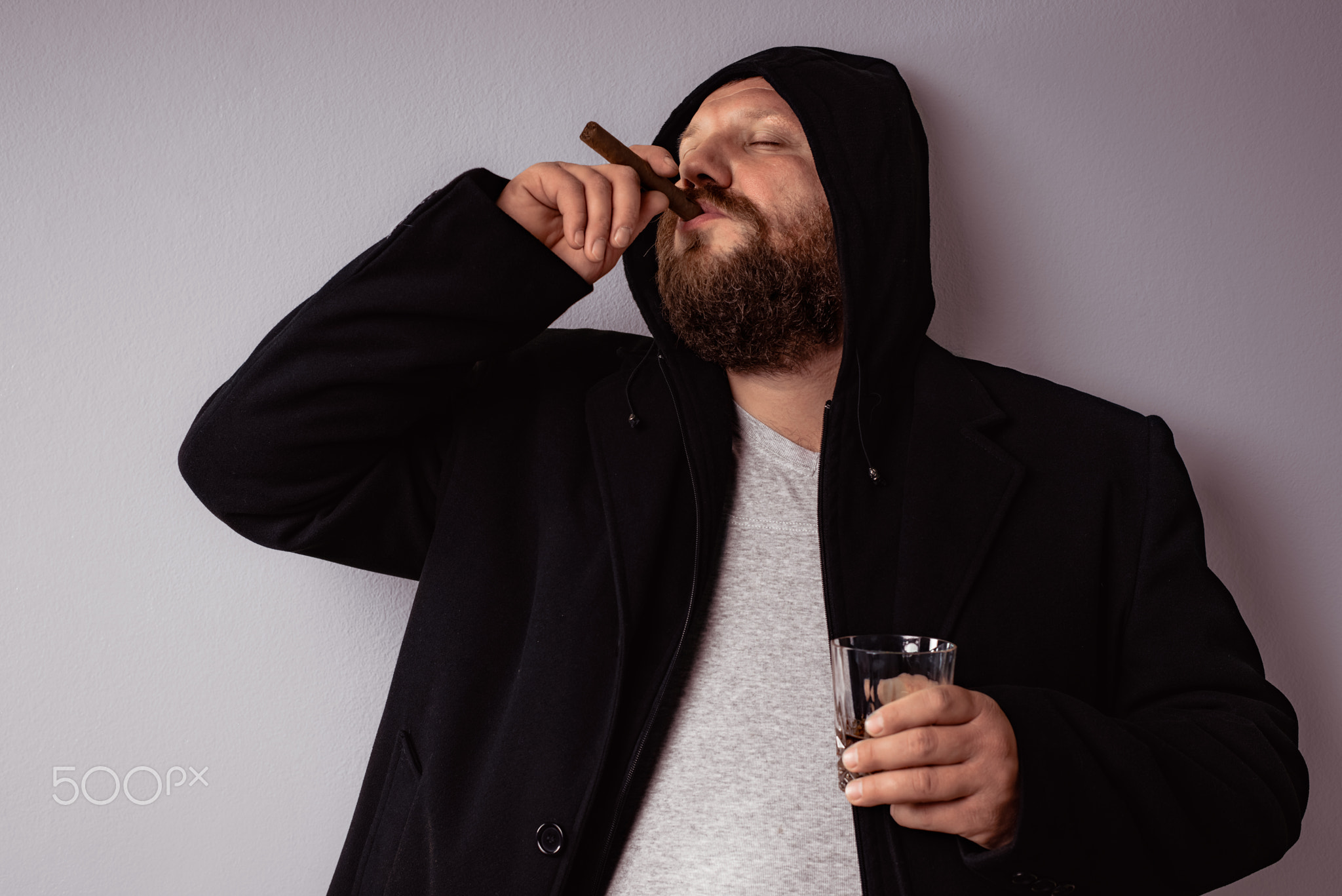 Handsome elegant bearded man wearing black coat with hood