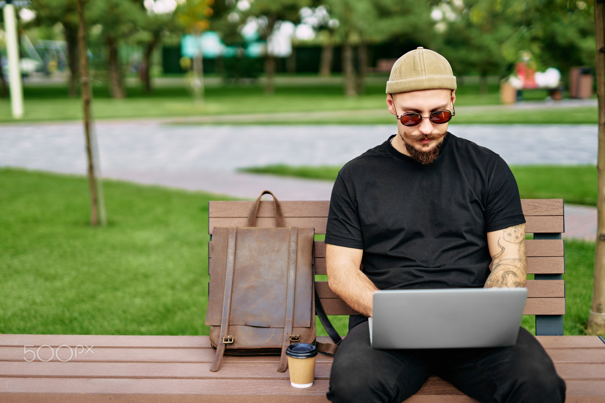 Man sits on the bench working, uses laptop with graphics, charts