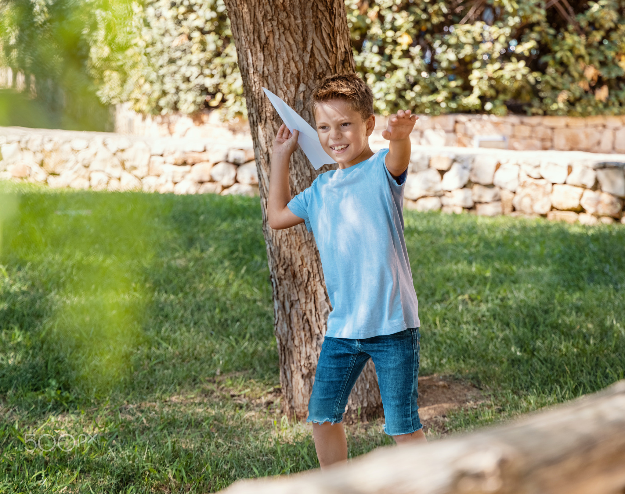 Happy Preschooler boy plays with a paper plane in park