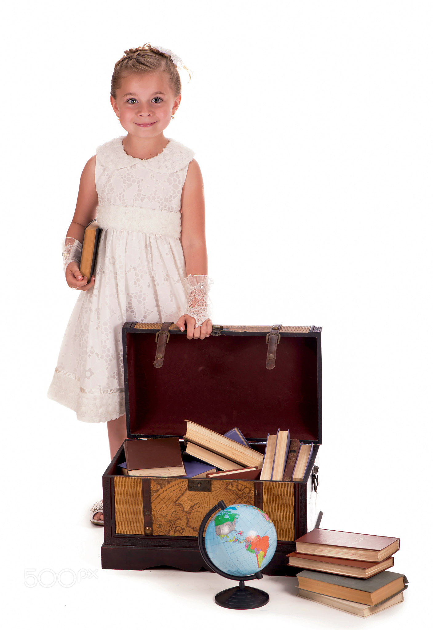 girl and a chest with books. little girl looking inside a trunk with
