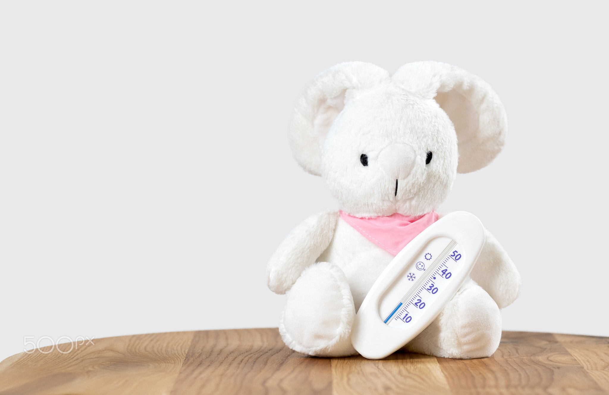 White toy rabbit with white thermometer sitting on the table