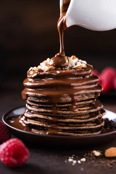 Chocolate pancakes with chocolate sauce pouring over