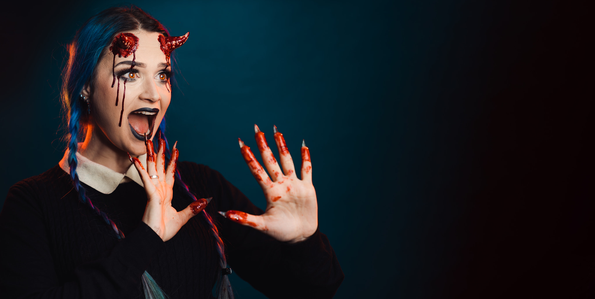 woman with scary halloween makeup with bloody horns dark background