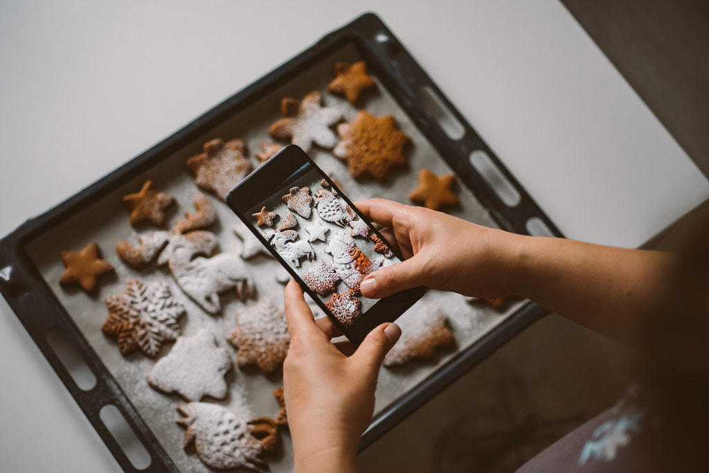 Woman takes photo on smartphone Christmas gingerbread sprinkled by Irina Evva on 500px.com
