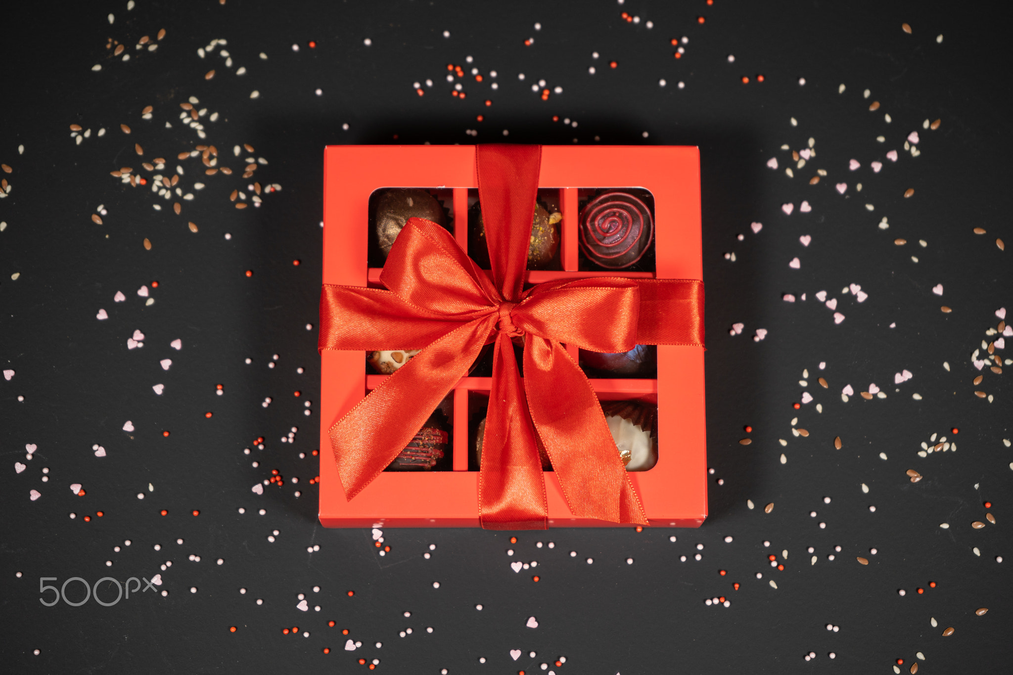 Various handmade chocolate truffle candies in a red box on a dark