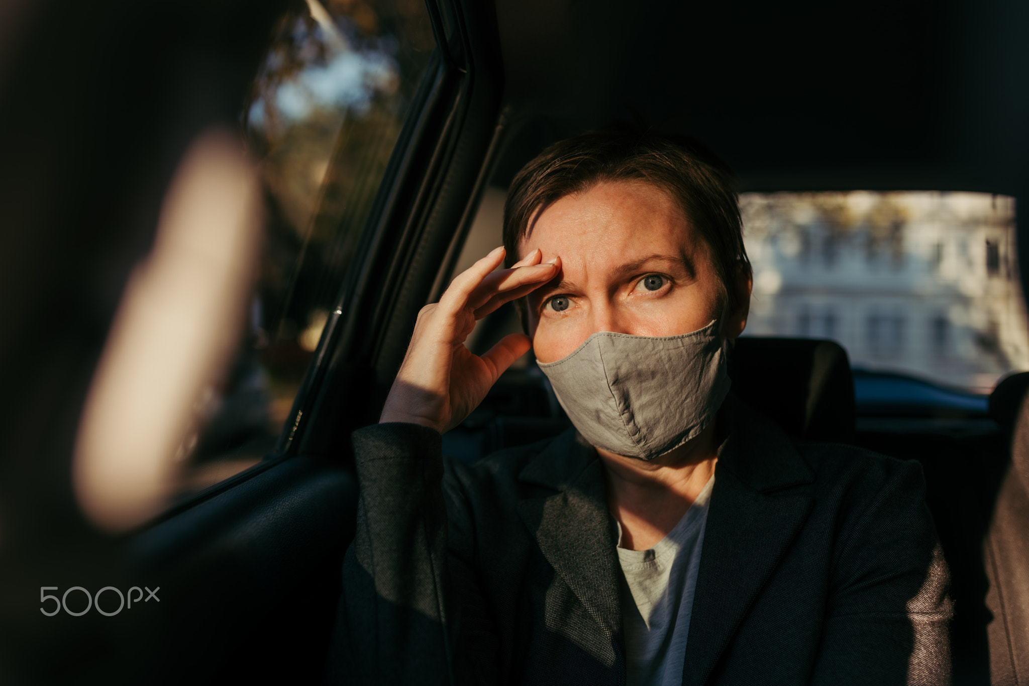 Anxious businesswoman sitting inside of the car and looking at camera