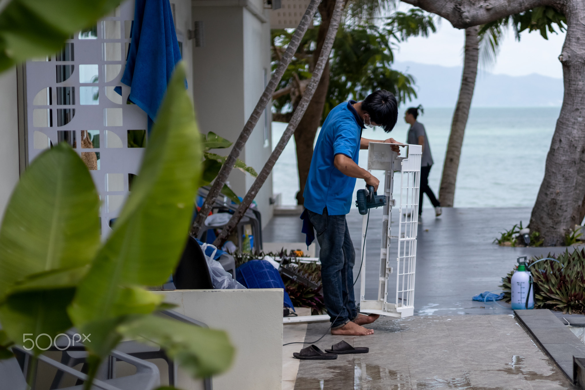 master men cleans the air conditioner in a tropical hotel.