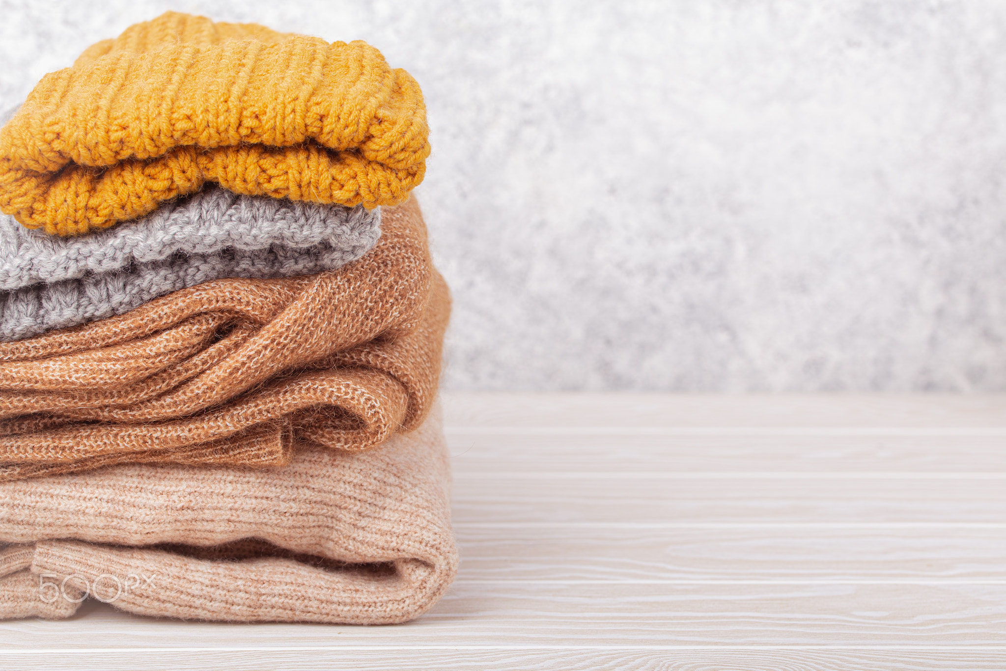 Pile of warm knitted clothes copy space