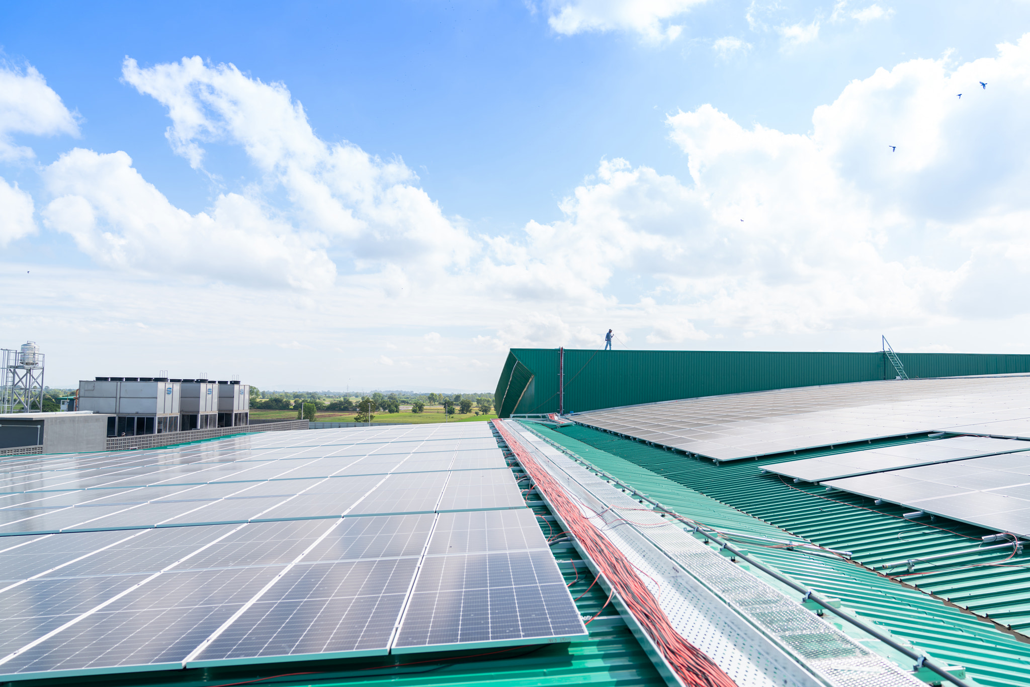 Worker wiring sola cell cable on roof top factory.