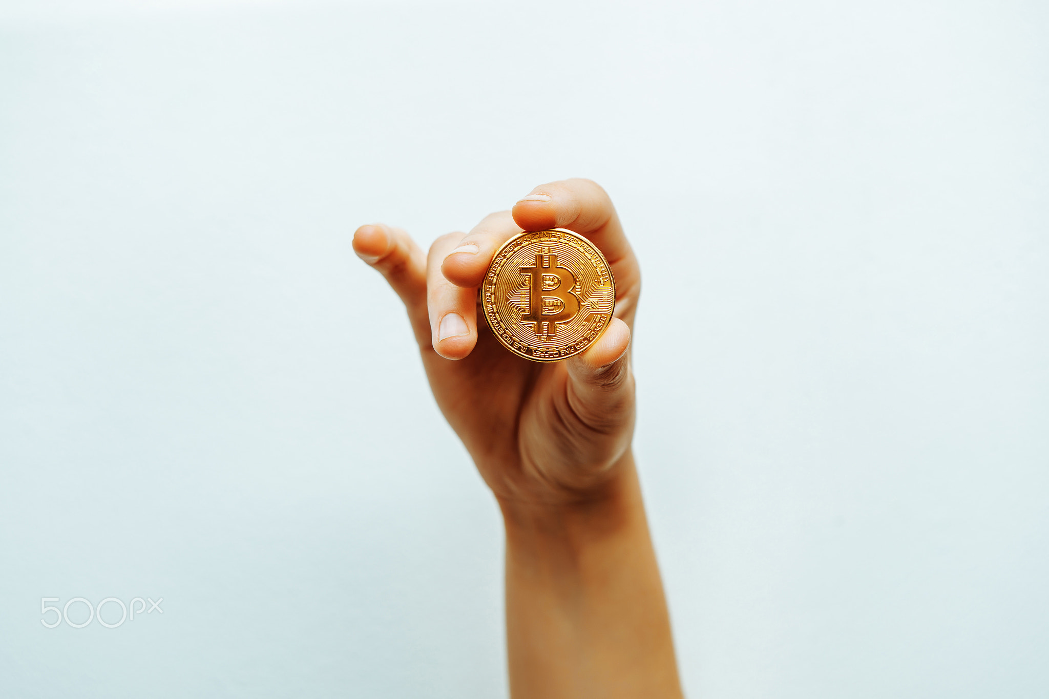 Bitcoin in hand on a light background.
