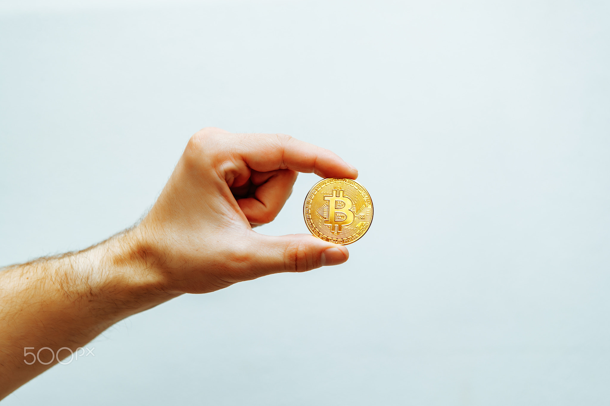 Bitcoin in hand on a light background.