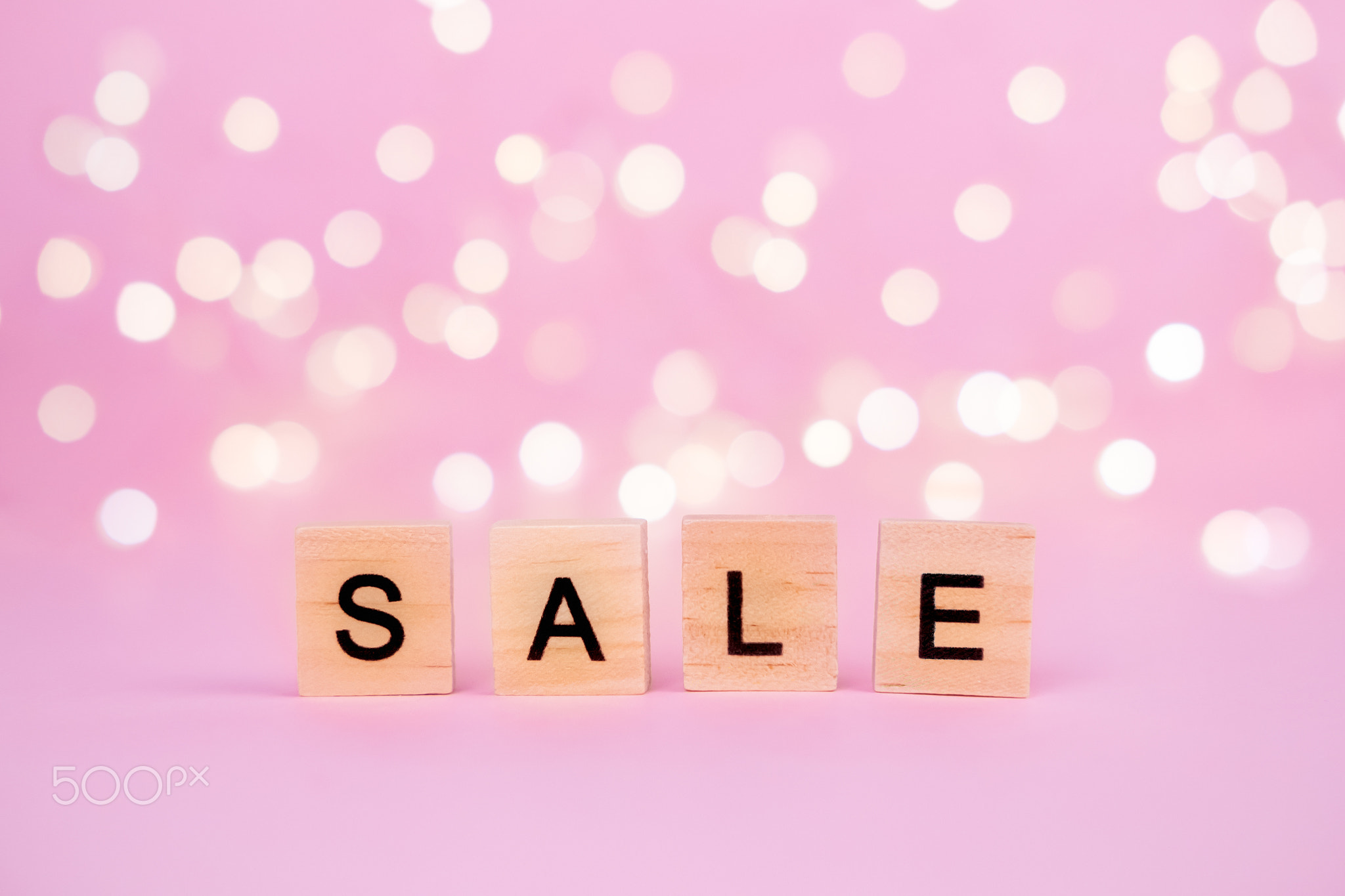 Words Sale on a blurred pink background with beautiful bokeh garland