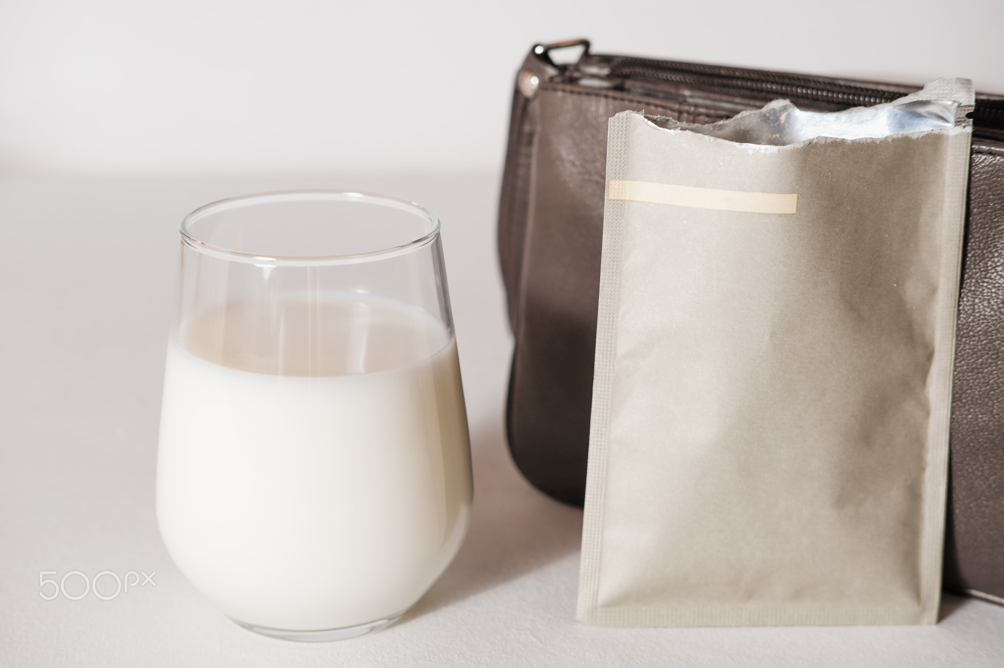collagen powder travel pack and a glass of milk to make protein