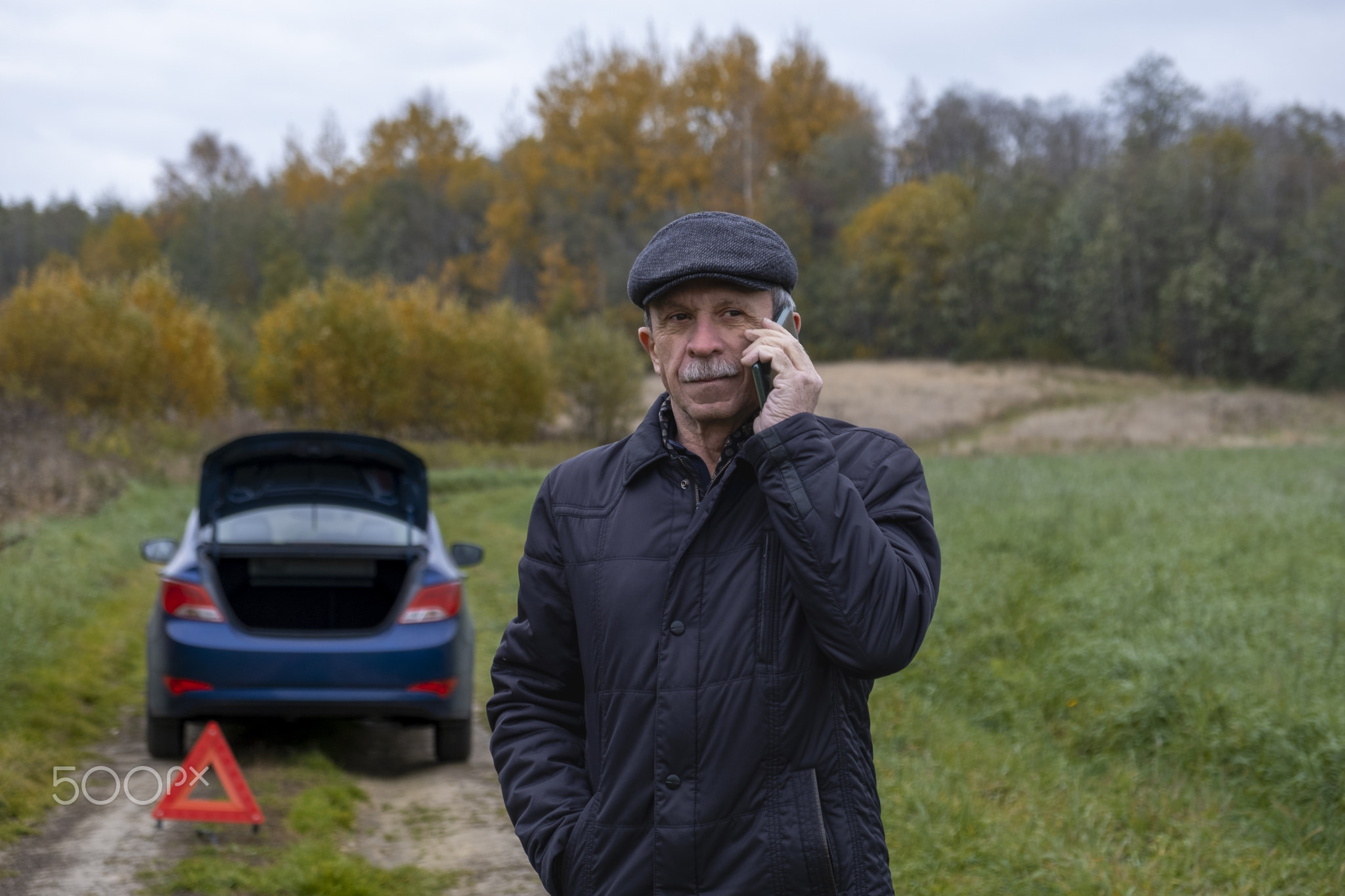 Adult pensioner calls technical assistance on smartphone after his car