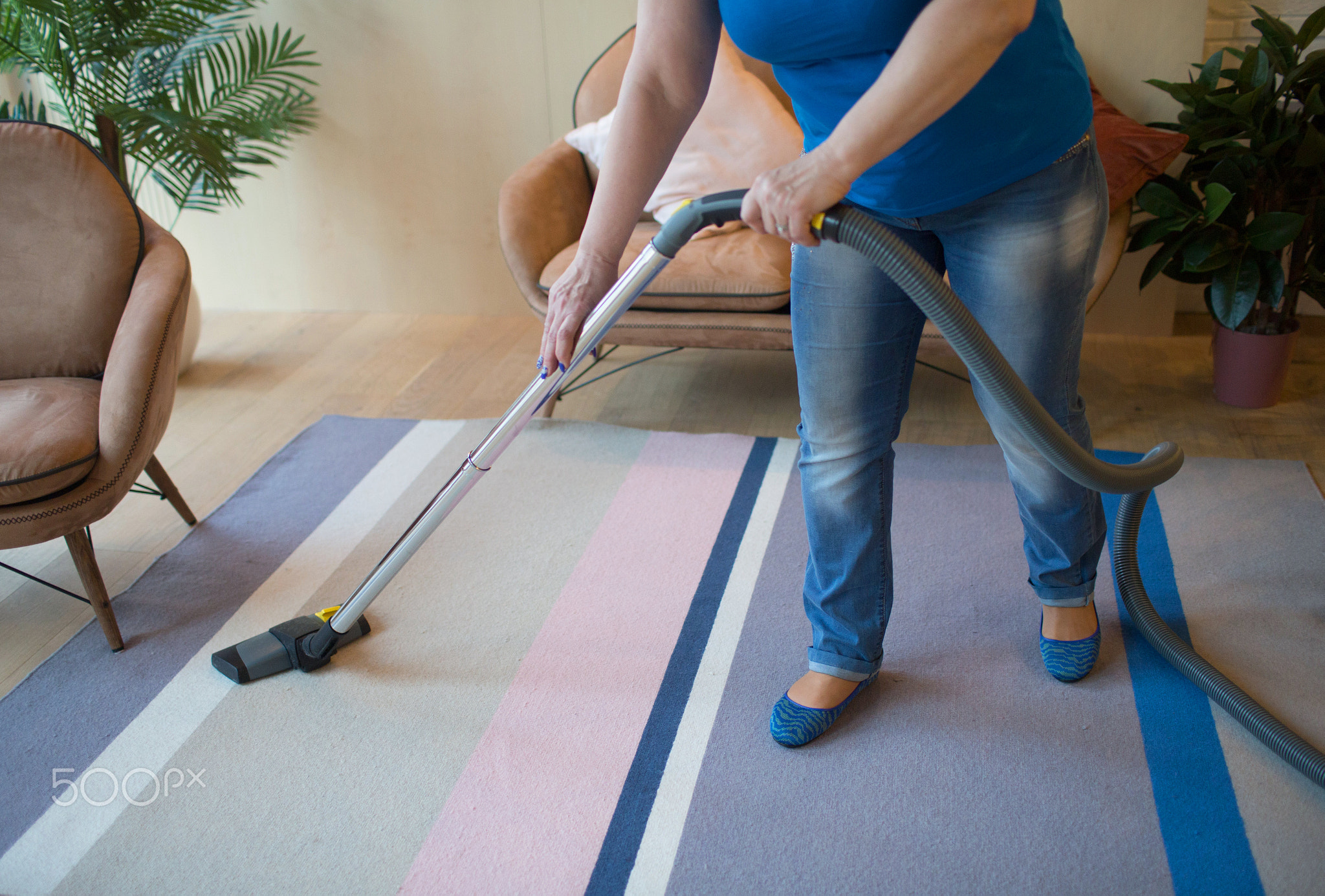 Cleaning service concept. Woman clean carpet with vacuum cleaner.