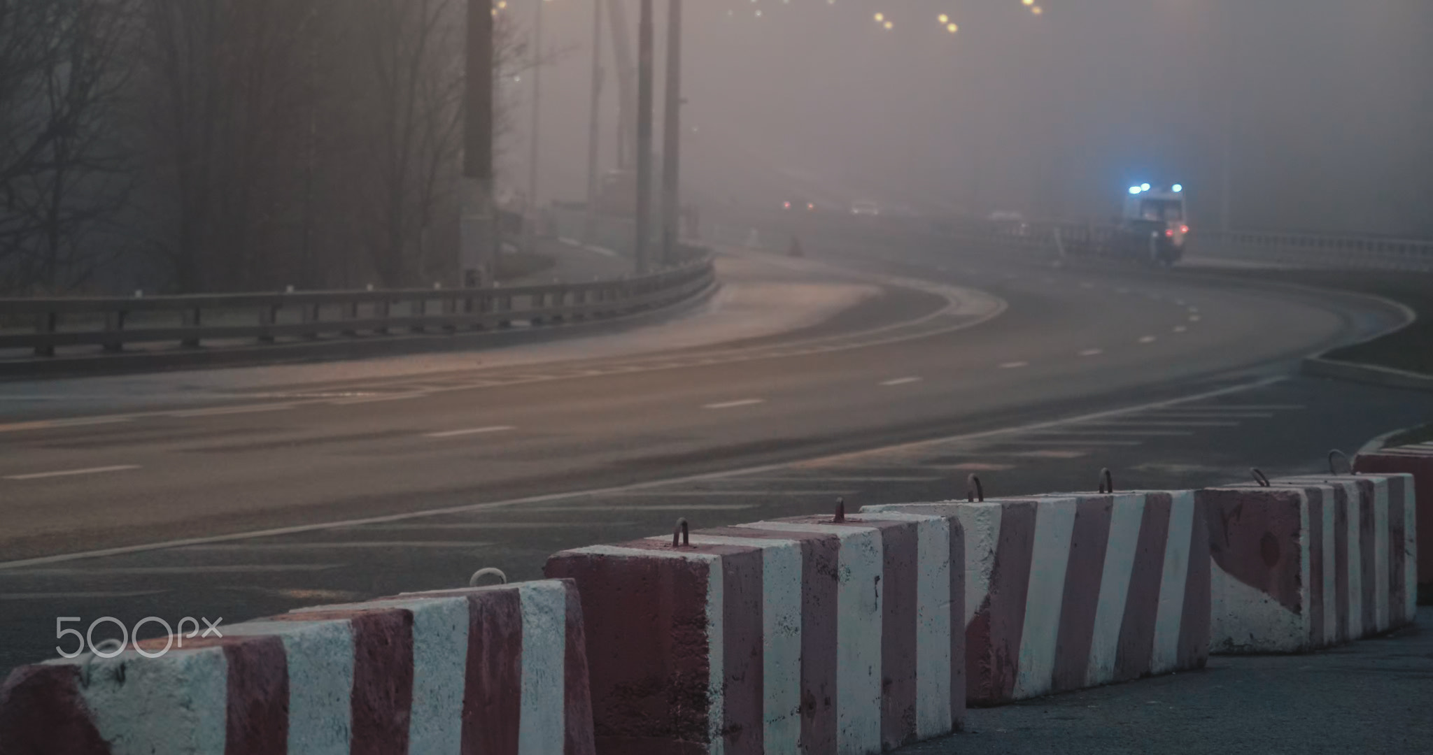 Night, thick fog over highway. Part of road is lockdown with concrete