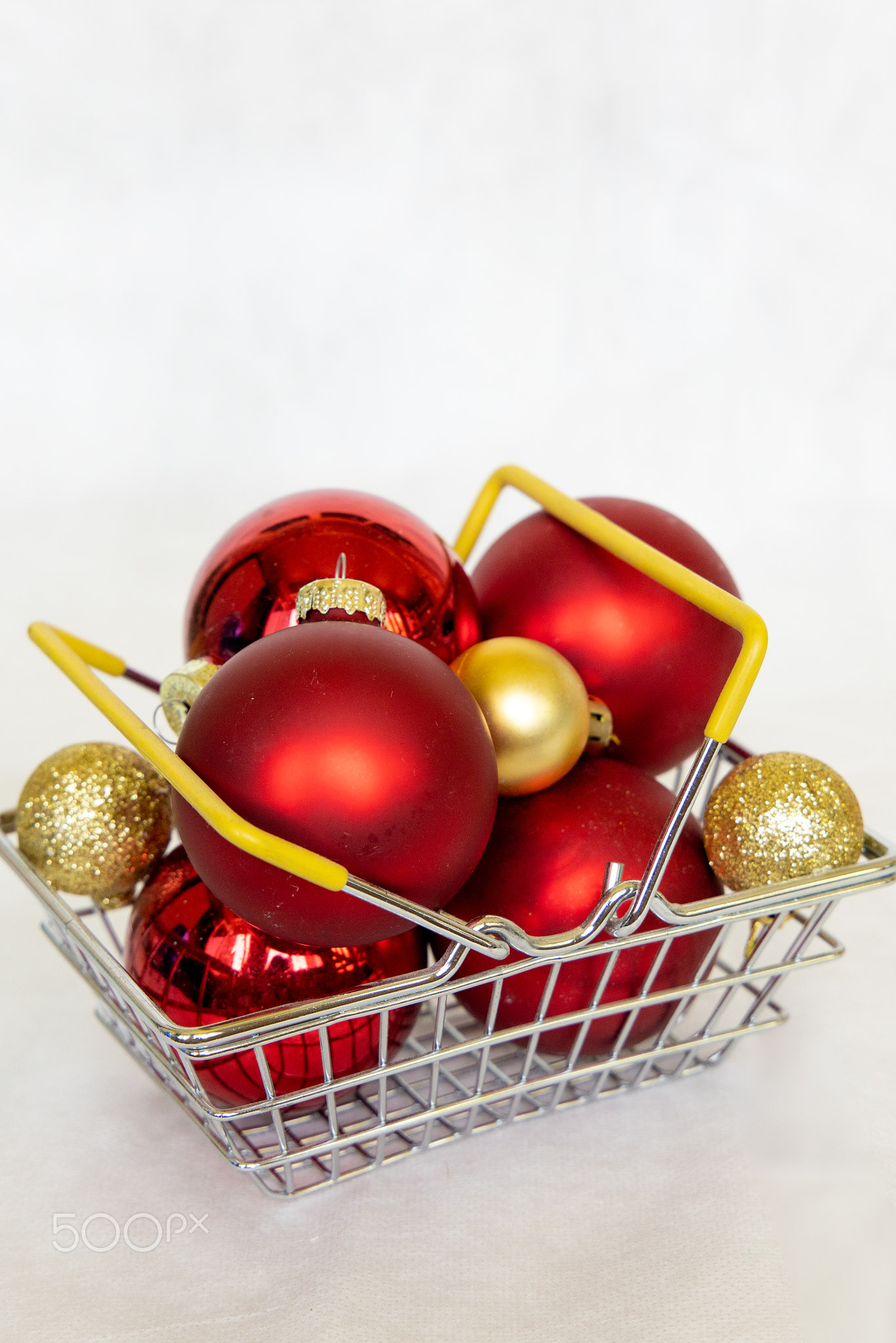 Red and gold Xmas balls in shopping cart. New year bubble.