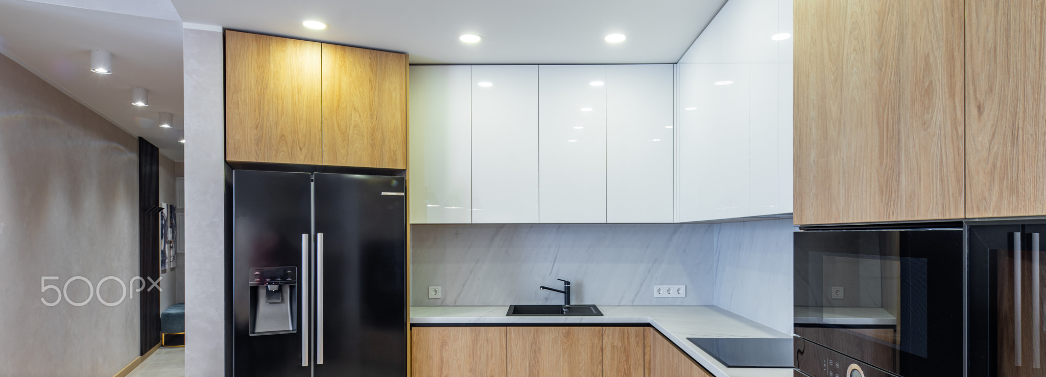 Modern interior of light wooden kitchen in apartment. White cabinets.