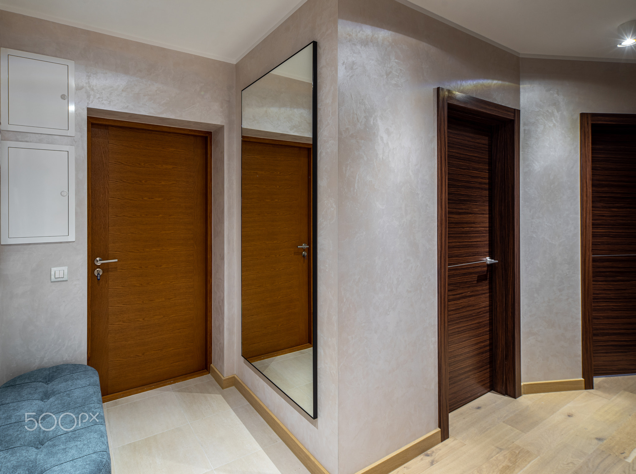 Modern interior of entrance hall. Wooden door. Velvet ottoman.