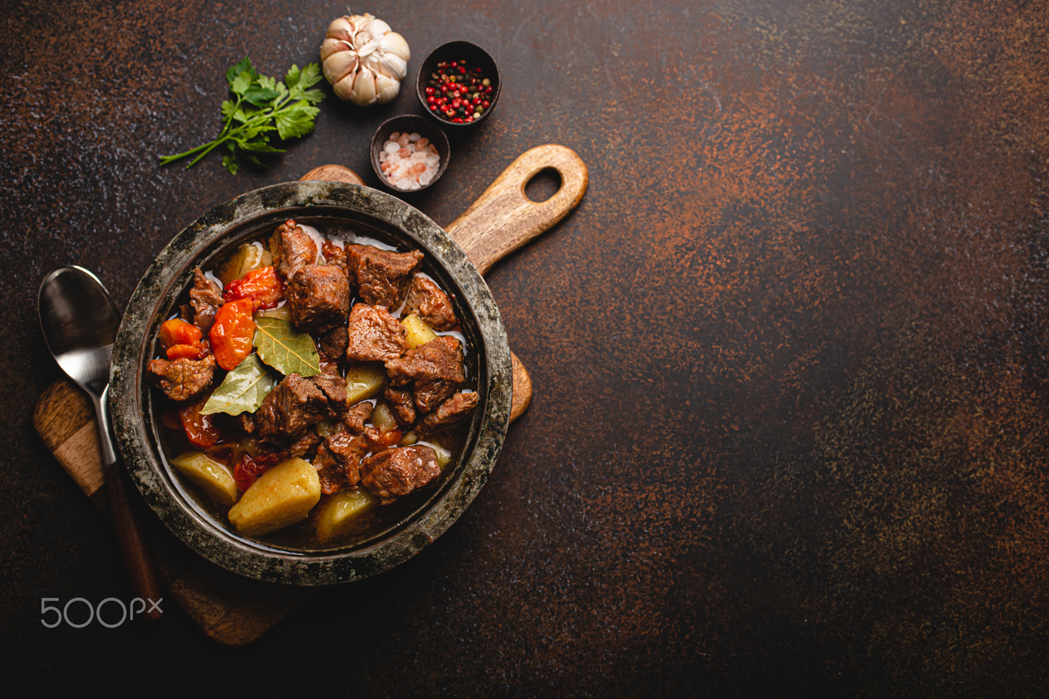 Meat beef stew with vegetables and gravy in rustic metal pot top view