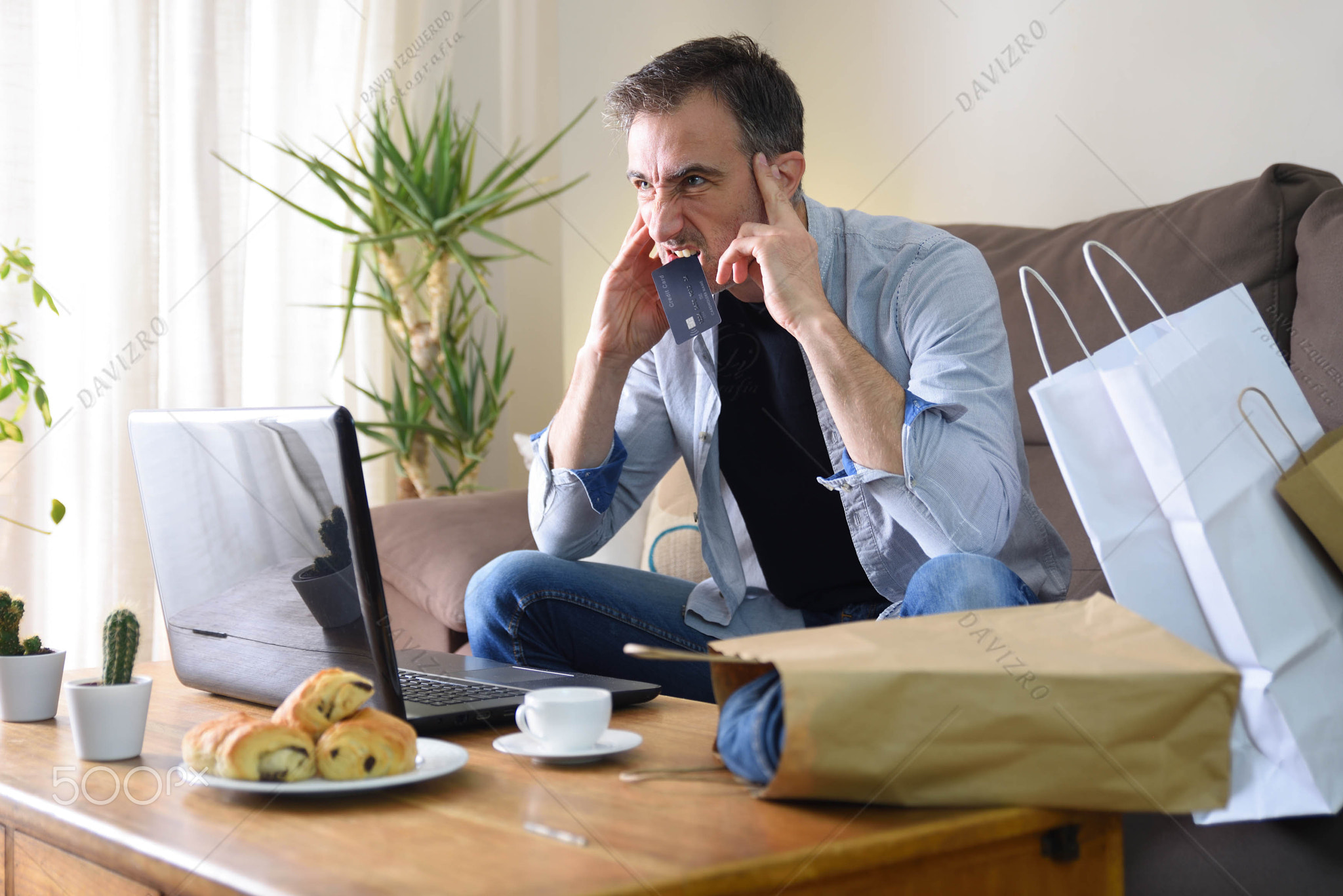 Angry man with online purchase biting credit card at home