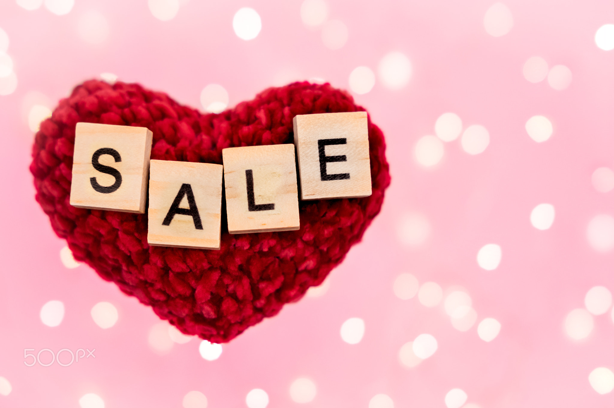 Word sale on red plush heart blurred pink background with copy-space