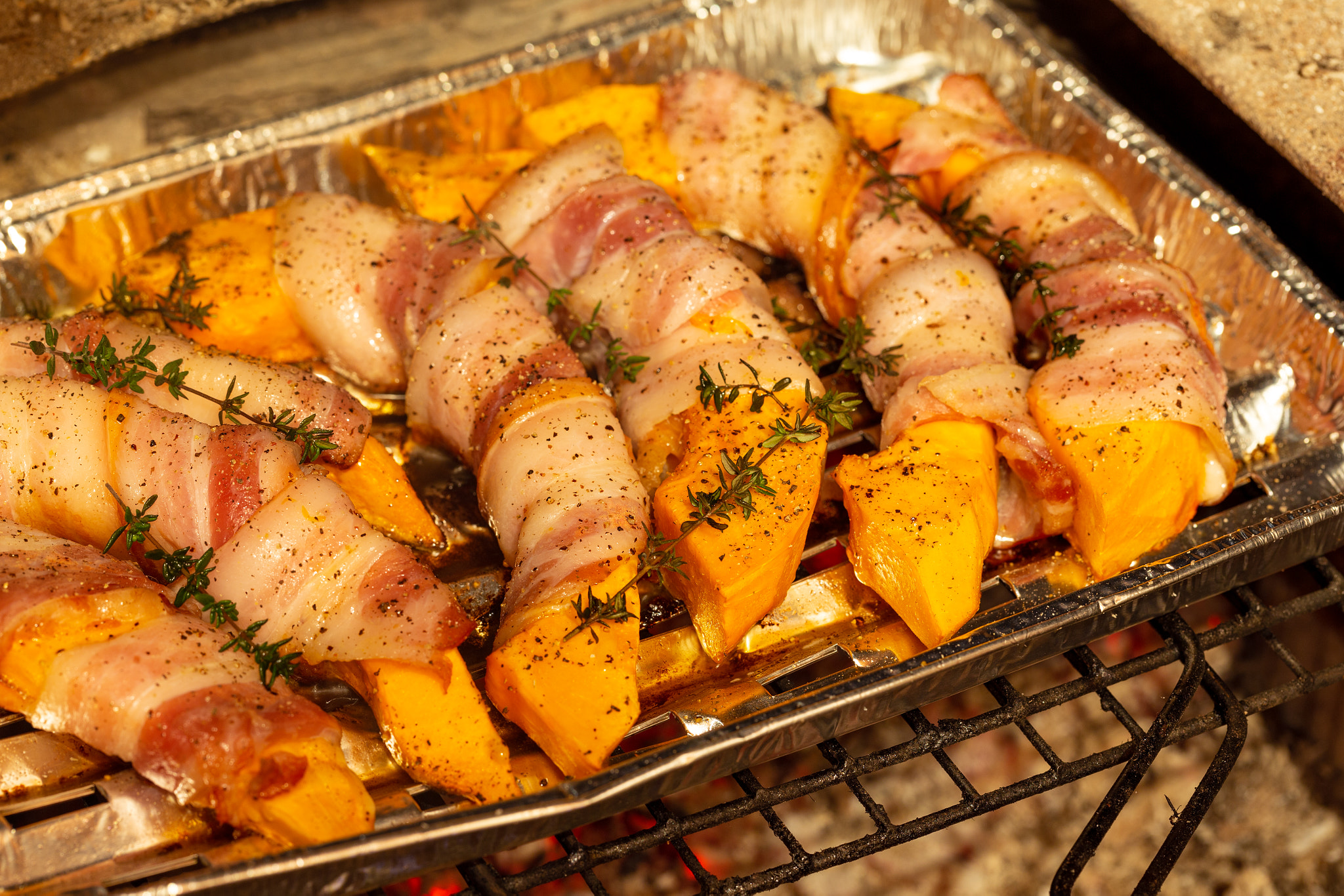 Delucious pumpkin slices wrapped in bacon grilled on charcoal